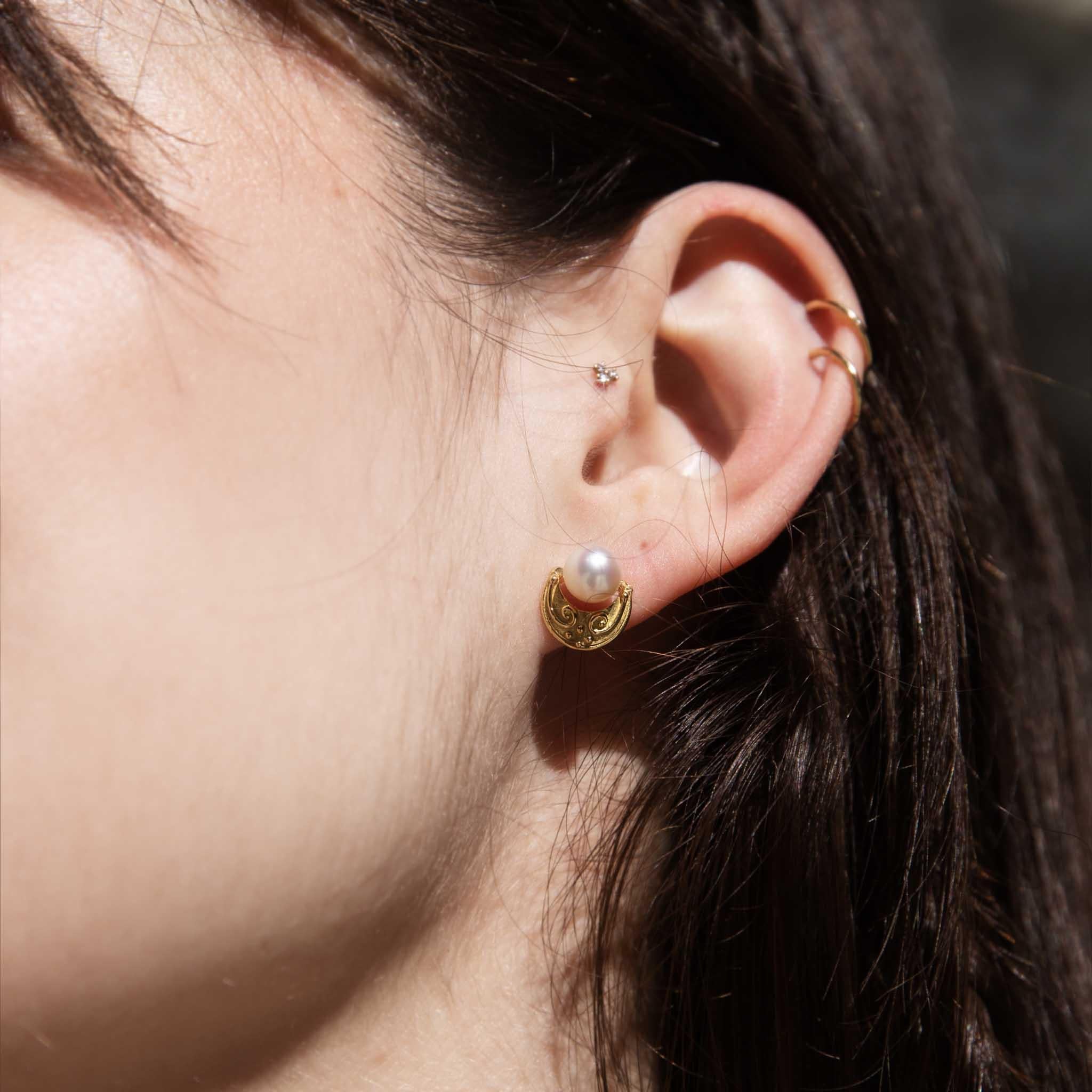Lustrous Akoya pearls, blessings of the ocean, are cradled in crescent moons of 18-carat gold. The warm glow of the settings dances with the iridescent pearls, while delicate swirls adorn the crescents, reminiscent of moonlit waves. The Antonia