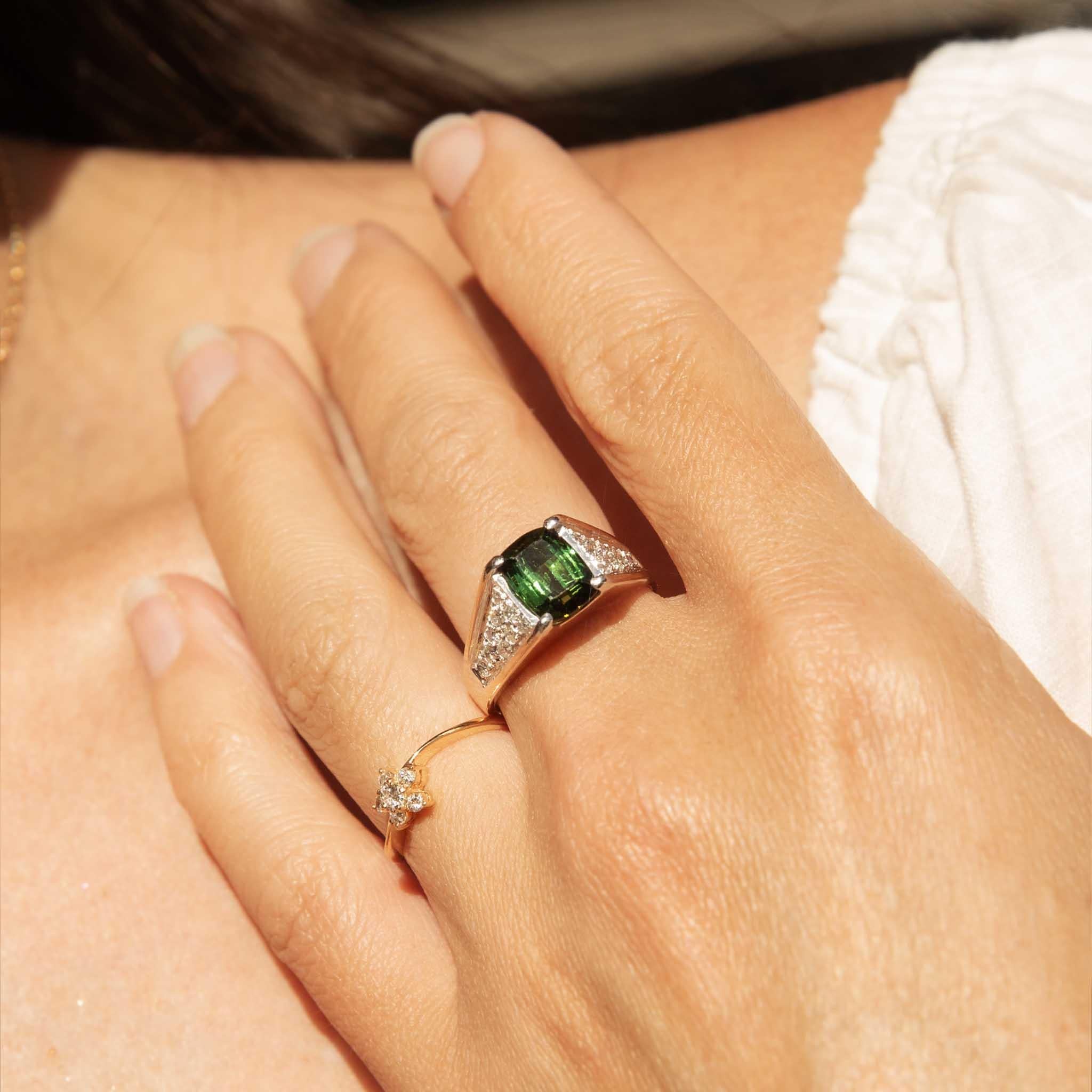 Joyau verdoyant, notre bague Collins est ornée d'une tourmaline d'un vert éclatant, dont la riche couleur rappelle celle d'une forêt luxuriante. Avec sa pierre précieuse de taille émeraude encadrée de diamants étincelants et son design audacieux en