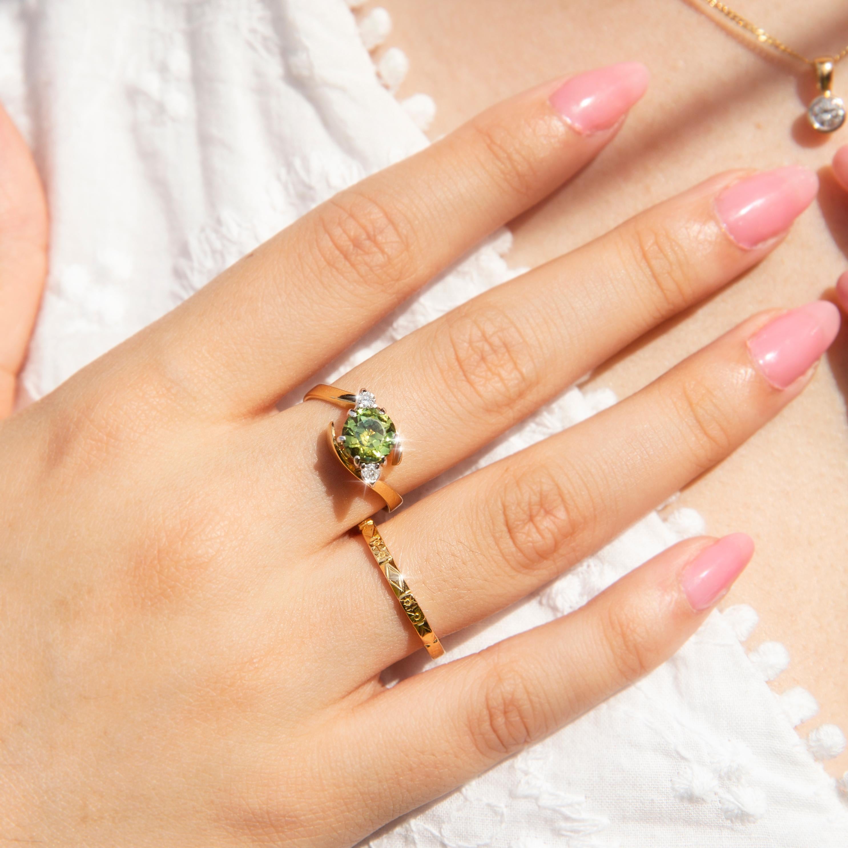 Dieser charmante Vintage-Ring aus 18 Karat Gelbgold aus den 1990er Jahren zeigt einen wunderschönen ovalen blau-grünen Partisan in einer Crossover-Fassung, die auf beiden Seiten von runden Diamanten im Brillantschliff flankiert wird. Dieser schöne
