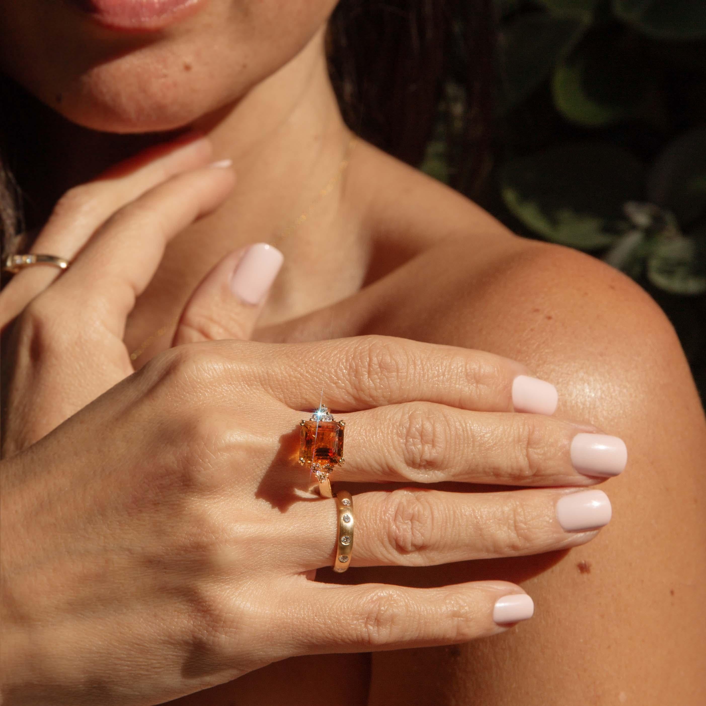 A golden flame caught in time, the Cachet Ring dazzles with an emerald-cut citrine of vivid orange fire, radiating warmth and confidence. Framed by a delicate array of six round brilliant cut diamonds, each a flicker of starlight, it rests in an