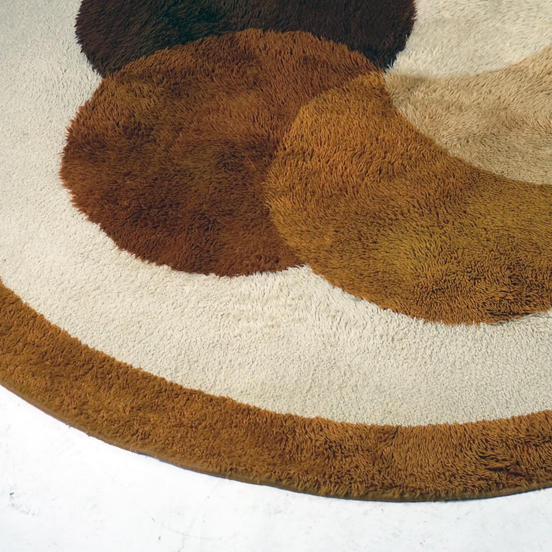 Ce tapis circulaire en laine marron, beige et jaune de l'âge de l'espace a été conçu et produit aux Pays-Bas par Desso dans les années 1970.
Tapis aux couleurs charmantes et aux motifs floraux très décoratifs en très bon état d'origine sans