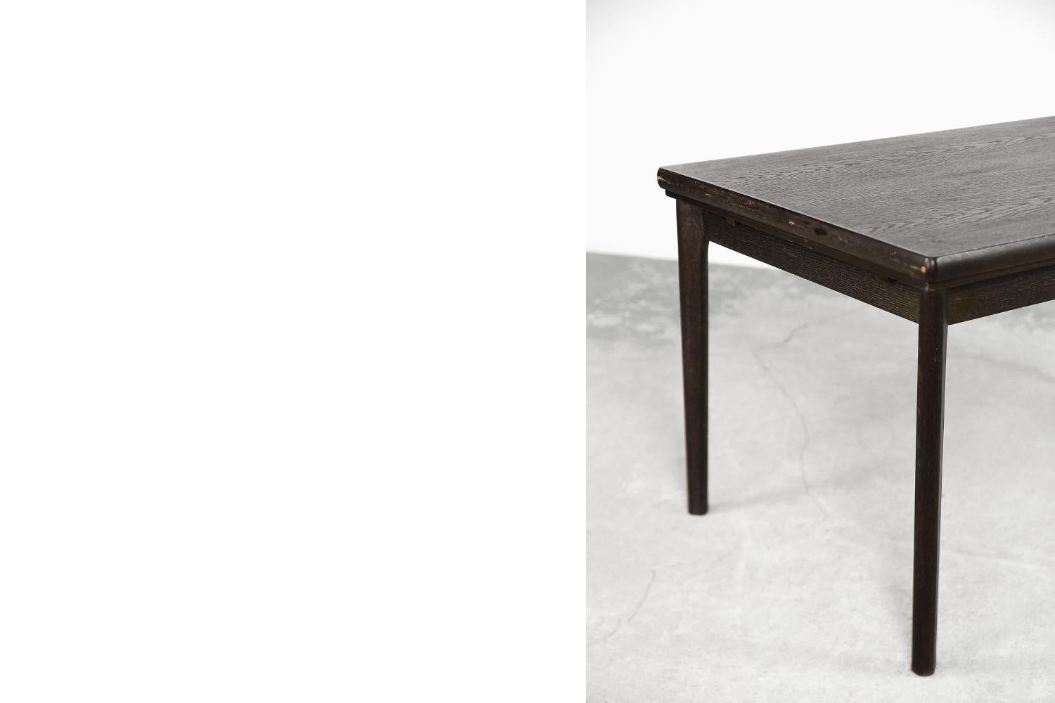Cette table de salle à manger classique a été produite par le fabricant danois AM Møbler [Ansager Møbler] dans les années 1960. Il est fabriqué en bois de chêne de haute qualité dans une teinte brune. Le grainage clair et le brossage léger lui