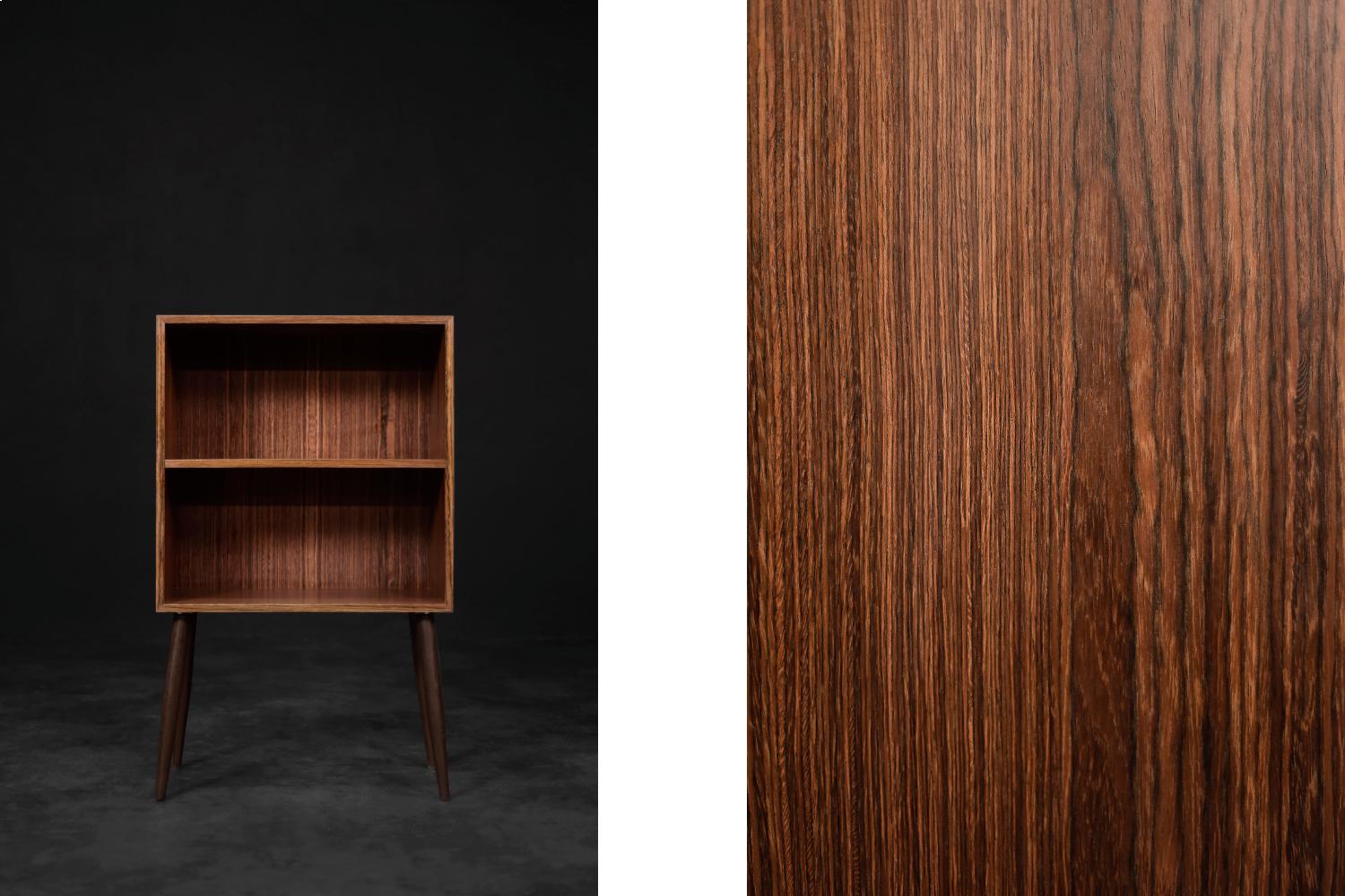 Ce meuble classique a été fabriqué au Danemark dans les années 1960. Il est fini en palissandre brun foncé avec un grain visible. L'armoire comporte deux étagères. Les pieds hauts et fins sont fabriqués en bois massif teinté en brun. L'armoire est
