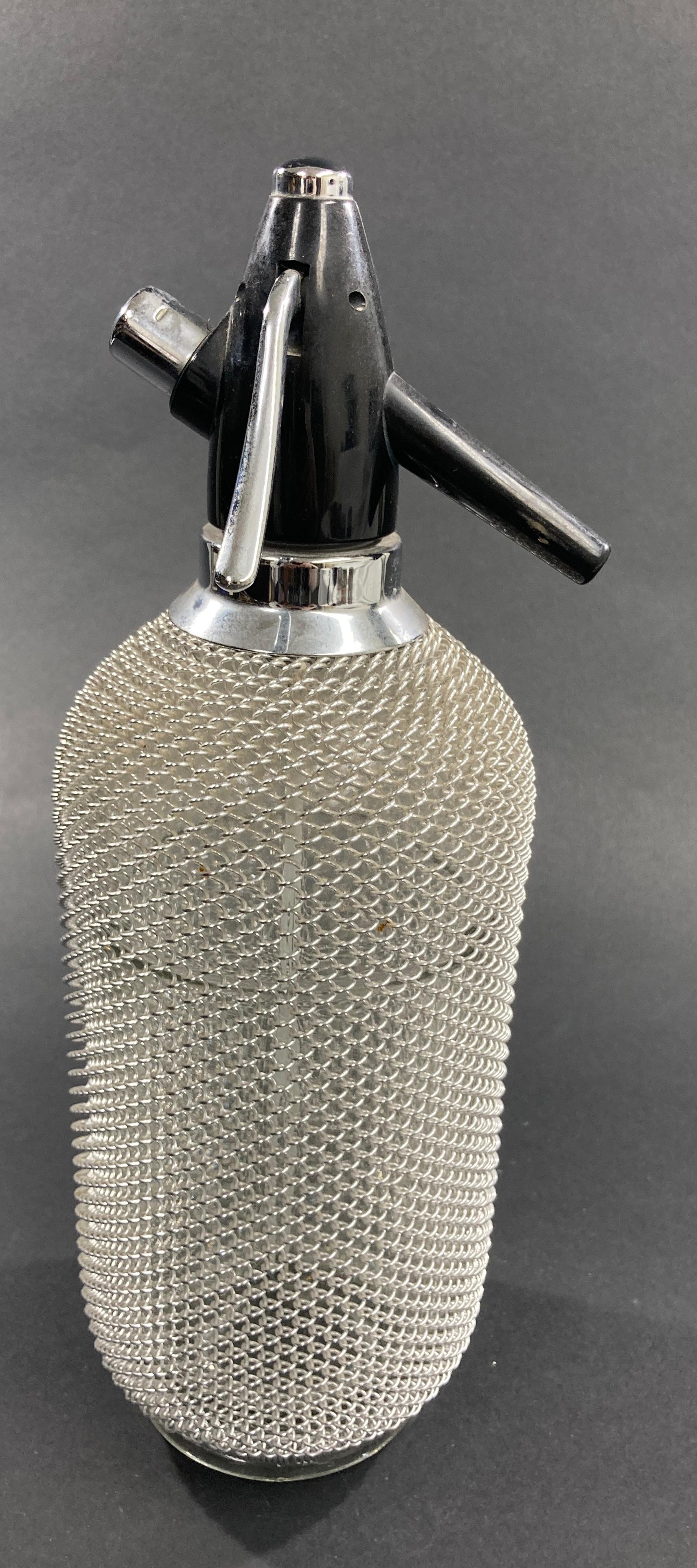 This is a fantastic vintage seltzer bottle with a metal wire mesh casing around the glass from the 1970.
Enjoy the fresh and healthy fizz of sparkling water, carbonated juice drinks, wine spritzers, and handcrafted cocktails. 
Vintage barware