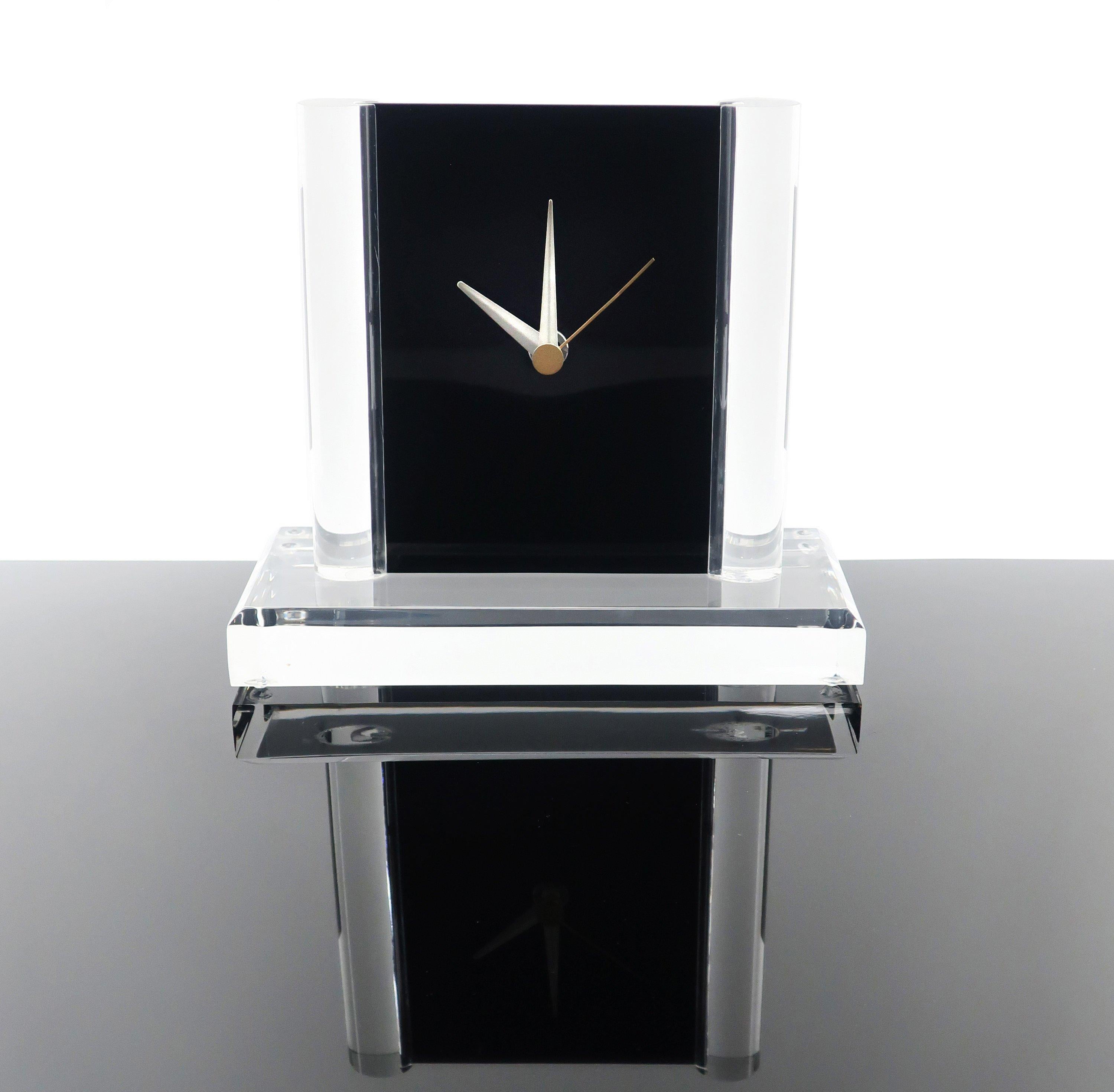 Set on a faceted clear Lucite base and round Lucite columns, the movement for this charming clock is housed inside two pieces of black acrylic that fit together and slide down into the base. Clean lines, simple elegance, and perfect modern