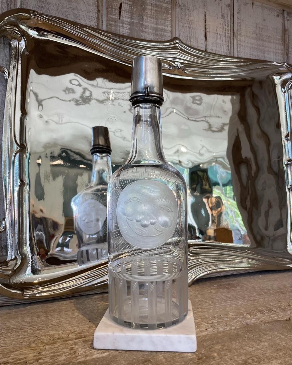 This fabulous vintage clear glass bottle decanter is intricately decorated with a large etched happy smiling full moon with a bold linear border design on the base. It is accented by a removable sterling silver shot glass top that can be locked onto