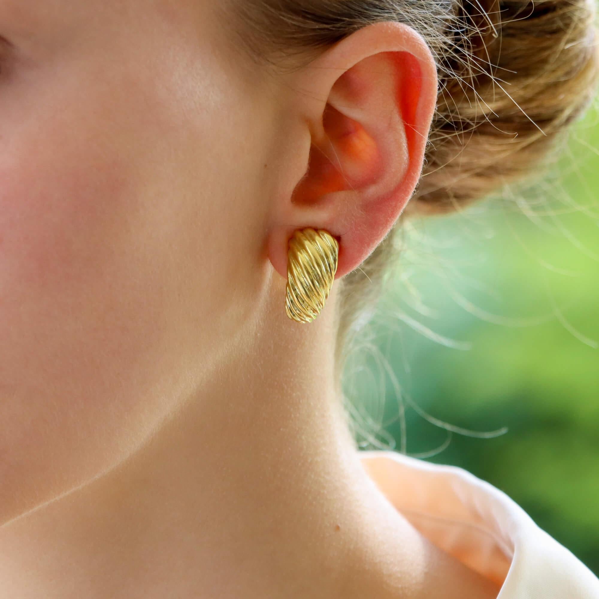  A beautiful vintage pair of retro inspired earrings set in 18k yellow gold.

Each earring is composed of a large half hoop, engraved with a subtle pattern that travels across the entire face of each earring. This grooved pattern creates a beautiful