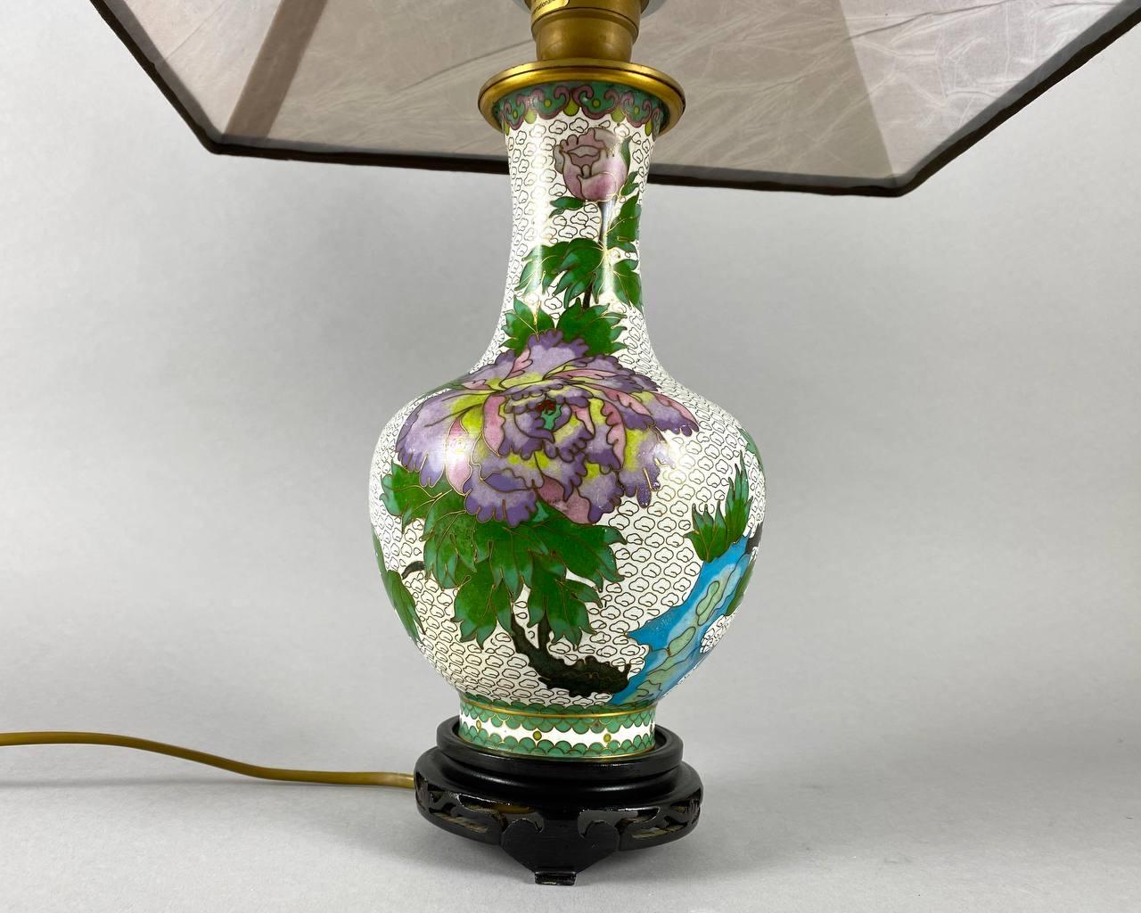 Lampe de table chinoise vintage. Vers les années 1970,  en métal, en émail, en textile, en peinture décorative.

La base de la lampe est réalisée sous la forme d'un vase avec un col haut et étroit. La base et le col du vase sont décorés de pivoines