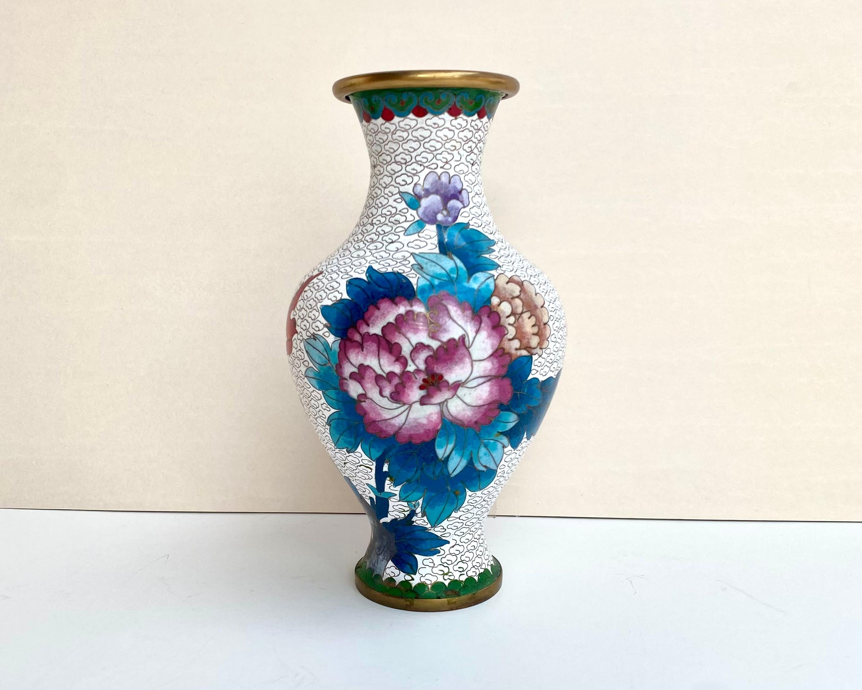 A vintage Chinese multicolor Cloisonne metal vase decorated with large flower pattern on the white background. 

The rim and the circular base bronze colored. This Cloisonné vase is finished in smooth enamel. 

The vase was created in China in