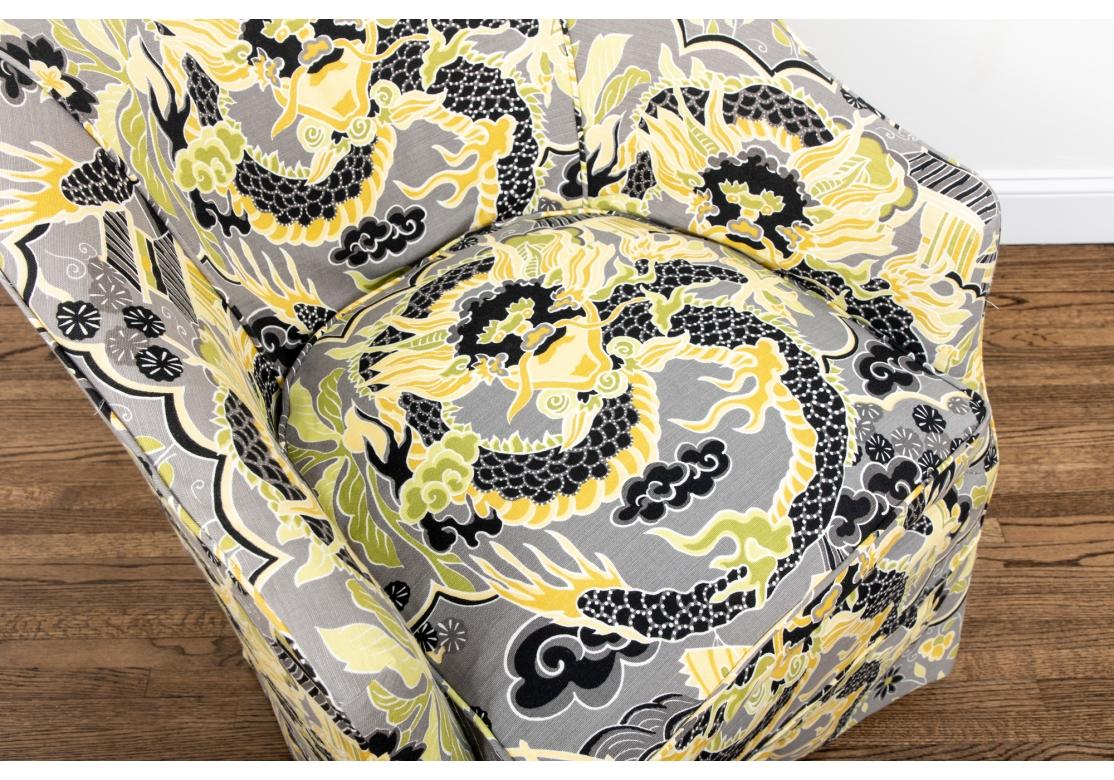 A comfortable club chair with curved sloping back and arms. Tightly slip covered in a sophisticated Asian style print in yellow, gray and black with a stylized dragon motif. With a deep tailored skirt over tapering fluted legs. 
H. 30