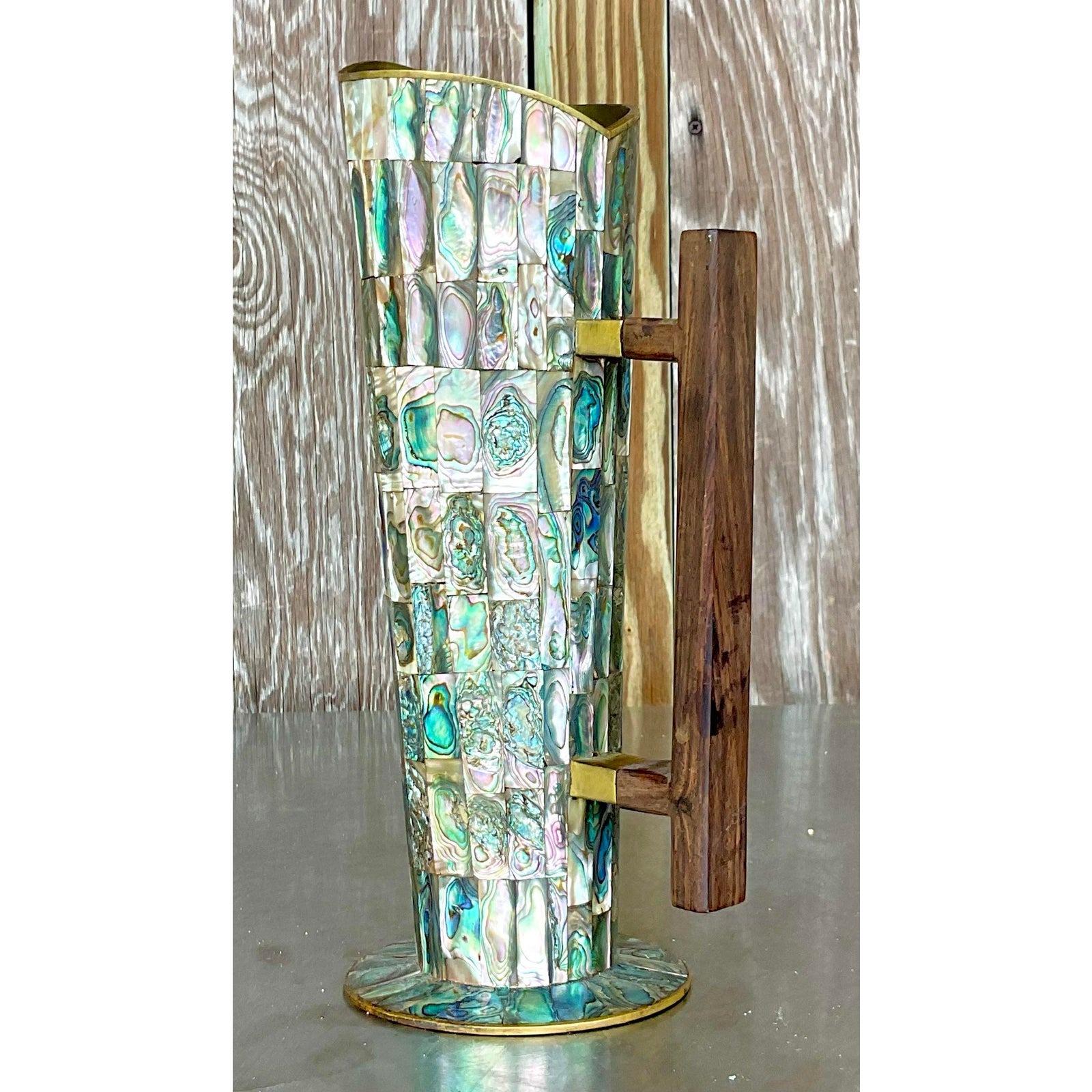Elevate your décor with the Vintage Coastal Abalone and Brass Pitcher. This American-style piece features stunning abalone inlay and elegant brass detailing, perfect for adding a touch of coastal charm and timeless sophistication to your home