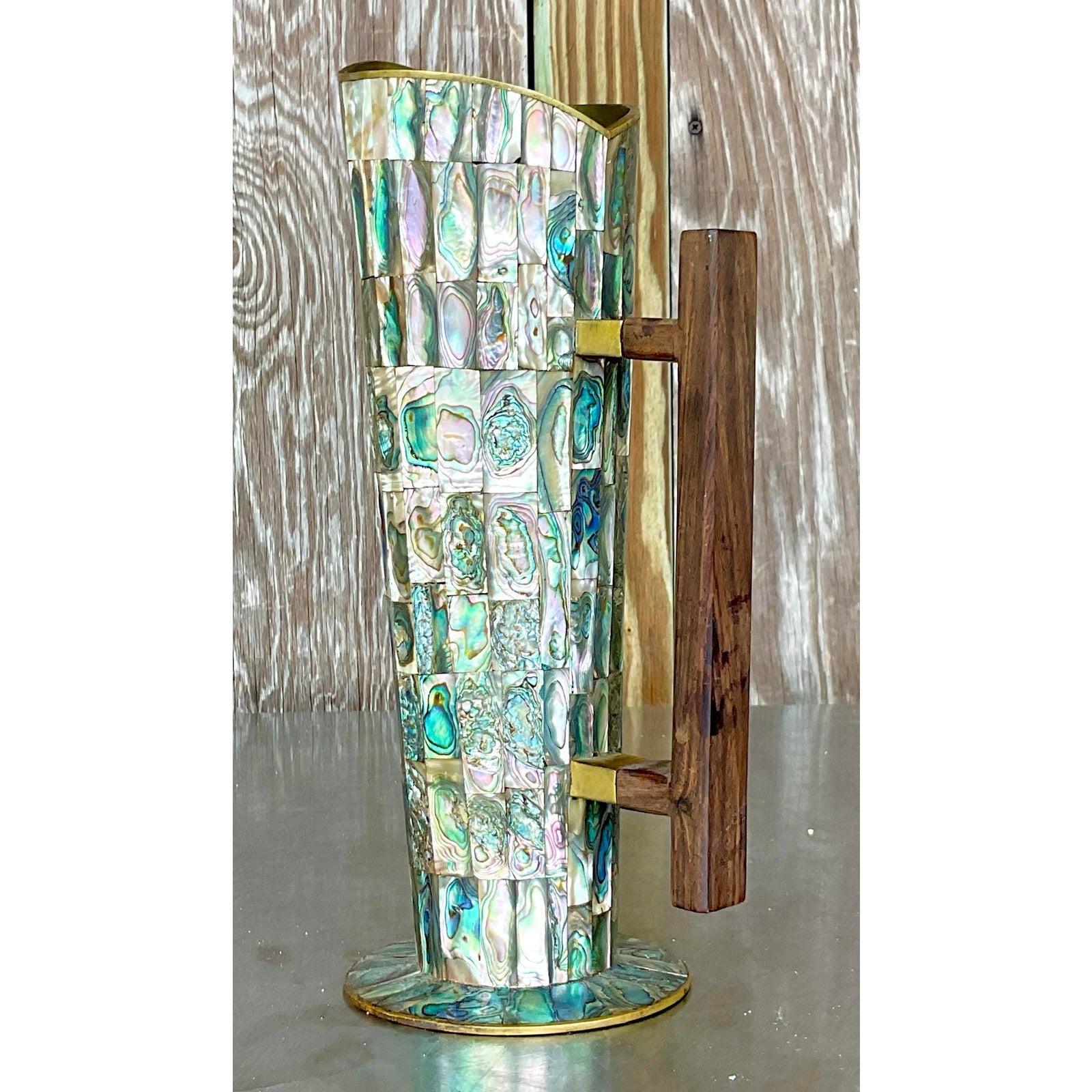 Eleva tu decoración con la Jarra Vintage Coastal de Abulón y Latón. Esta pieza de estilo americano presenta impresionantes incrustaciones de abulón y elegantes detalles de latón, perfectos para añadir un toque de encanto costero y sofisticación