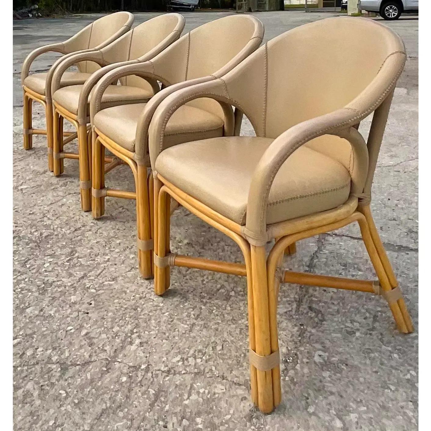 Fantastic set of 4 vintage Coastal dining chairs. Made by the iconic Antonio Budji. Gorgeous fawn color leather with whipstitch detail. Rattan frame and legs. Tagged on the bottom. The chicest dining chairs I have seen in a long time. Acquired from