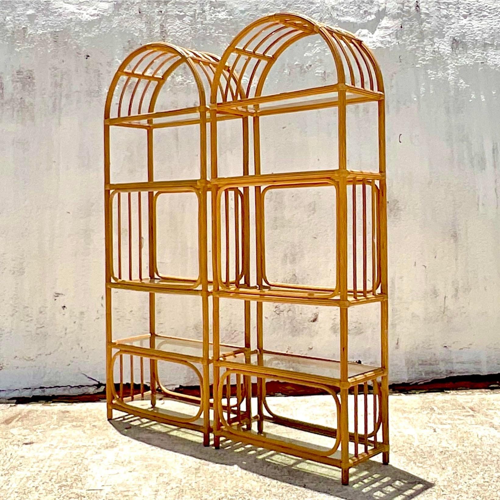 A fabulous pair of vintage Coastal etagere. Beautiful pencil reed construction in a chic arched design. Inset glass shelves. Acquired from a Palm Beach estate.