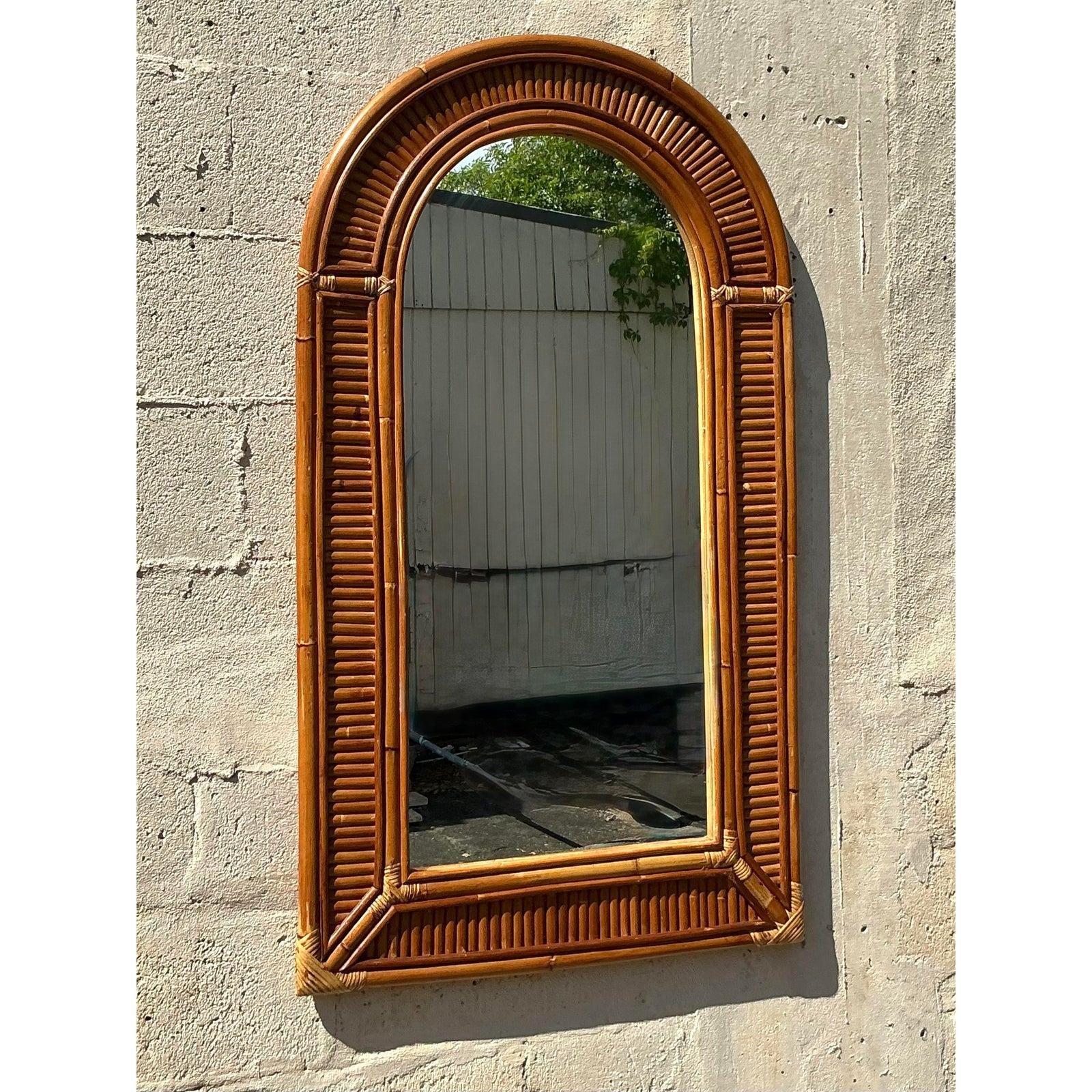 Questo specchio vintage in rattan ad arco dona una texture calda e naturale e un'eleganza costiera senza tempo a qualsiasi spazio. Con il suo piano graziosamente curvo e la struttura in bambù a coste, questo pezzo cattura il fascino rilassato ma