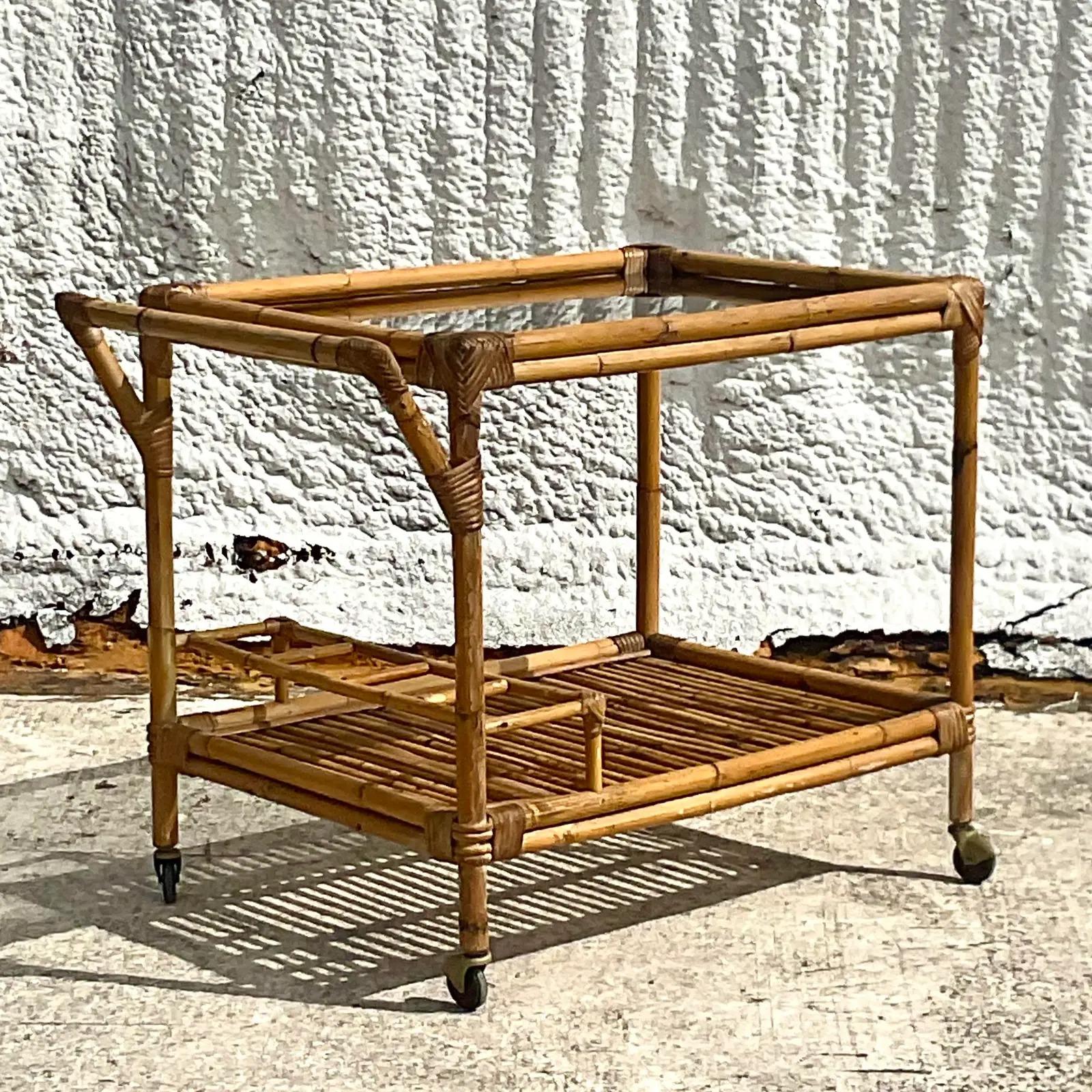 A fantastic vintage coastal bar cart. A chic bamboo construction with caster feet. Inset glass top. Acquired from a Palm Beach estate.