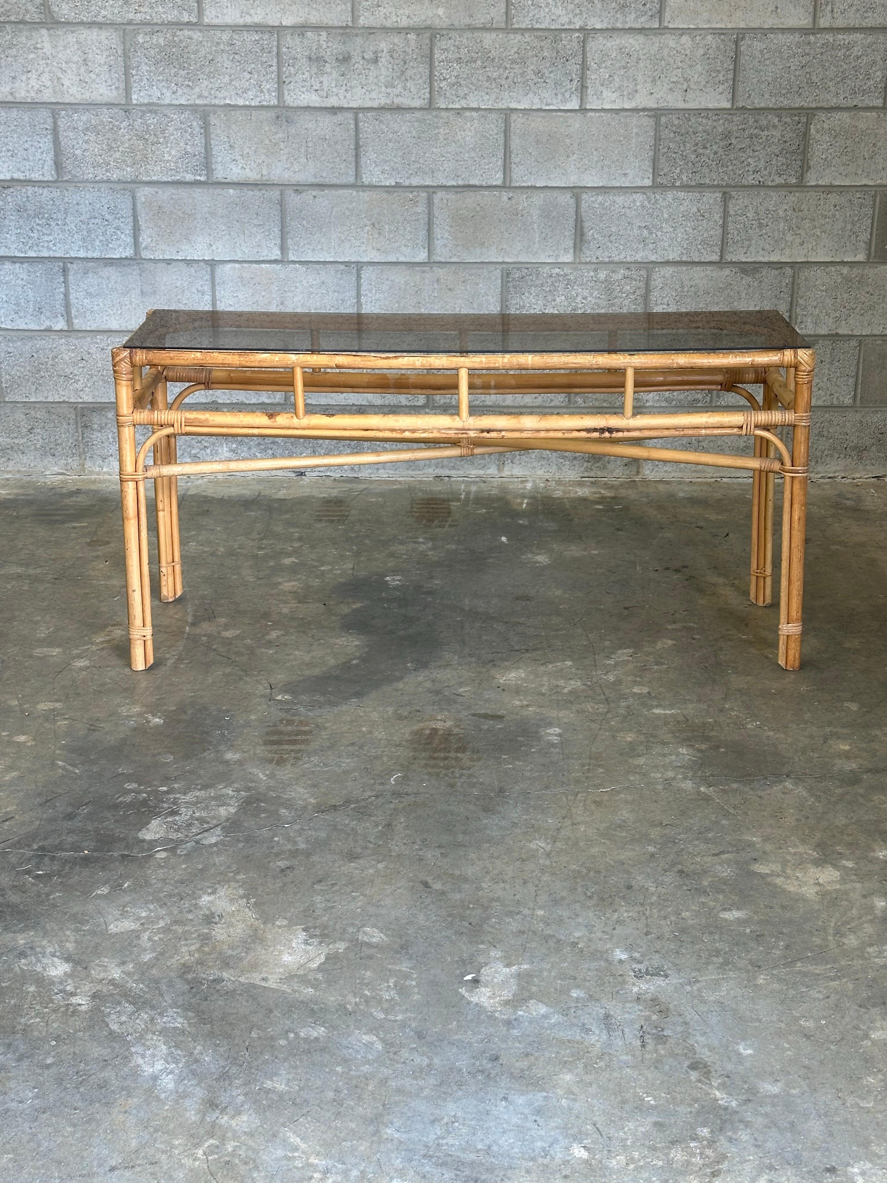 Wonderful vintage bamboo console table in a coastal or boho chic style. Bamboo frame with cane wrapped joints, completed with a tinted glass top. Would work in so many interior styles.

Similar to Ficks Reed, Willow and Reed, Maitland Smith, etc