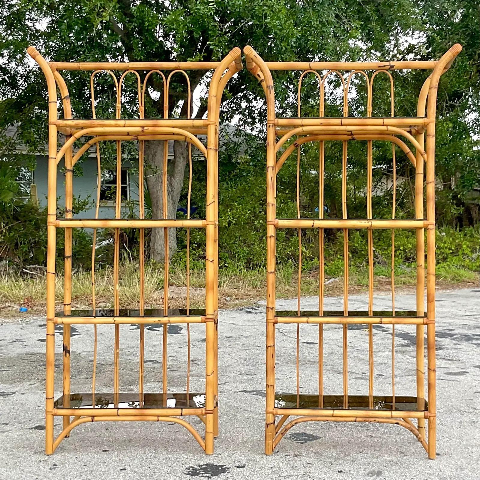A fantastic pair of vintage Coastal Etagere. Beautiful bamboo frames with a chic flare at the the crown. Tinted glass shelves complete the look. Acquired from a Palm Beach estate.