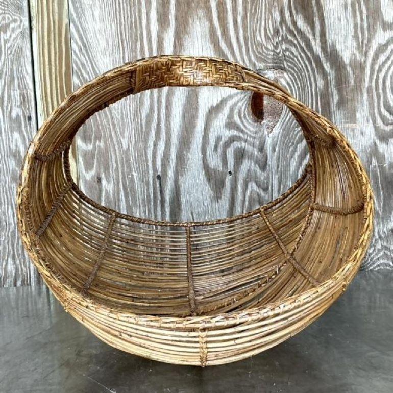 Fangen Sie die Essenz des Küstencharmes mit diesem Vintage Coastal Bent Rattan Basket ein. Handgefertigt aus natürlichem Rattan, bringen die fließenden Kurven und die organische Textur eine entspannte, strandähnliche Atmosphäre in jeden Raum. Dieser