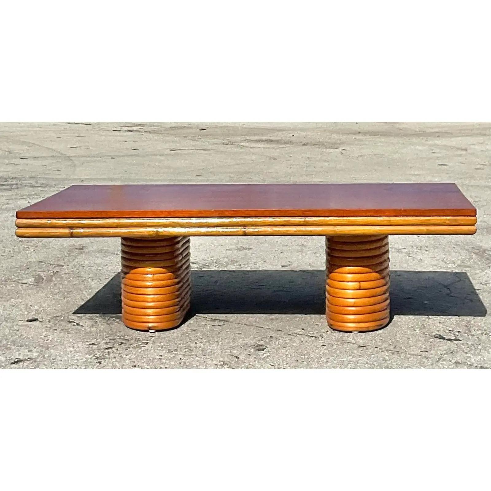 Incredible vintage coastal bent rattan coffee table. Done in the manner of Paul Frankl. Beautiful wood grain detail on top with rattan pedestals below. Acquired from a Palm Beach estate.