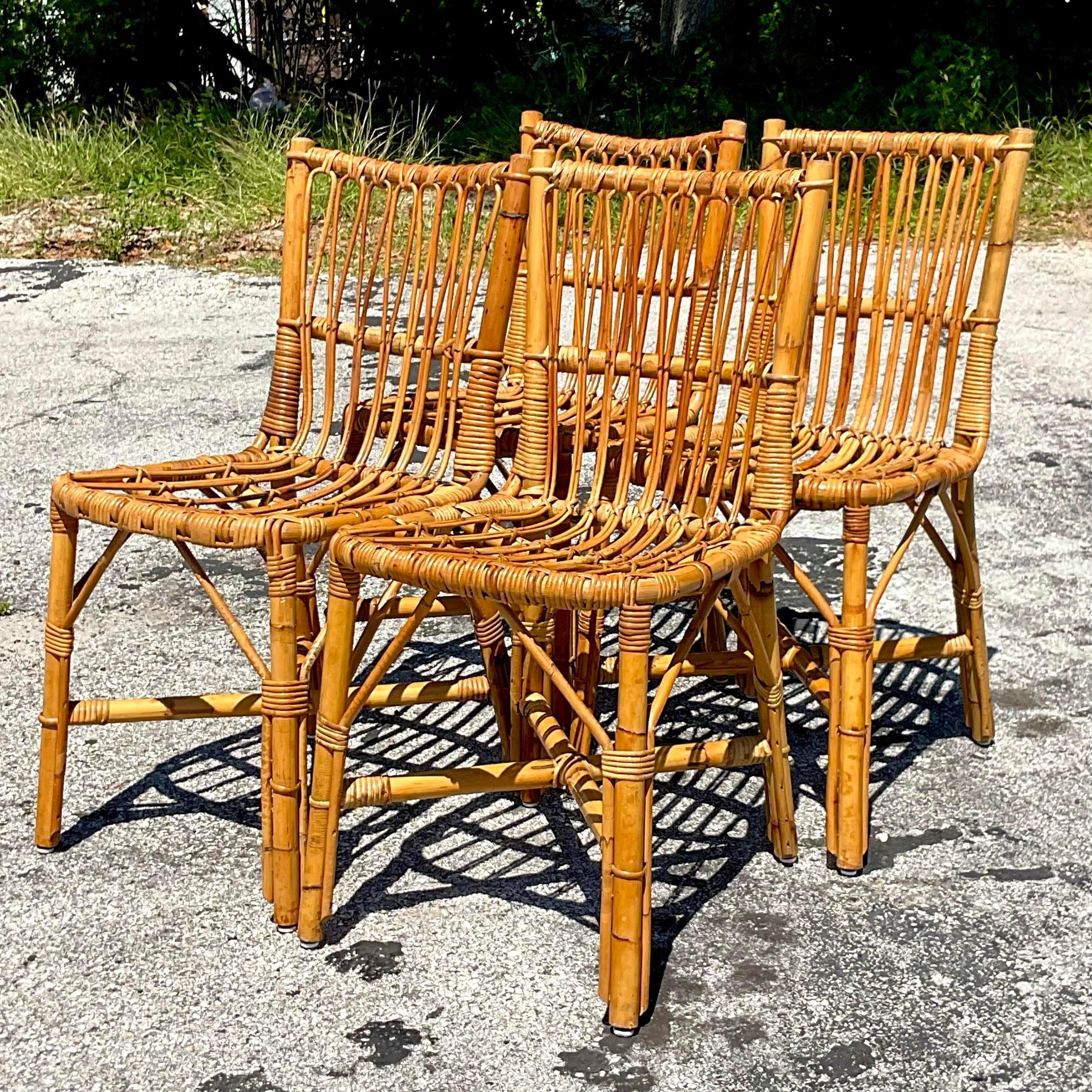 A fabulous set of four vintage Coastal dining chairs. A chic bent rattan in a clean and open design. Acquired from a Palm Beach estate.