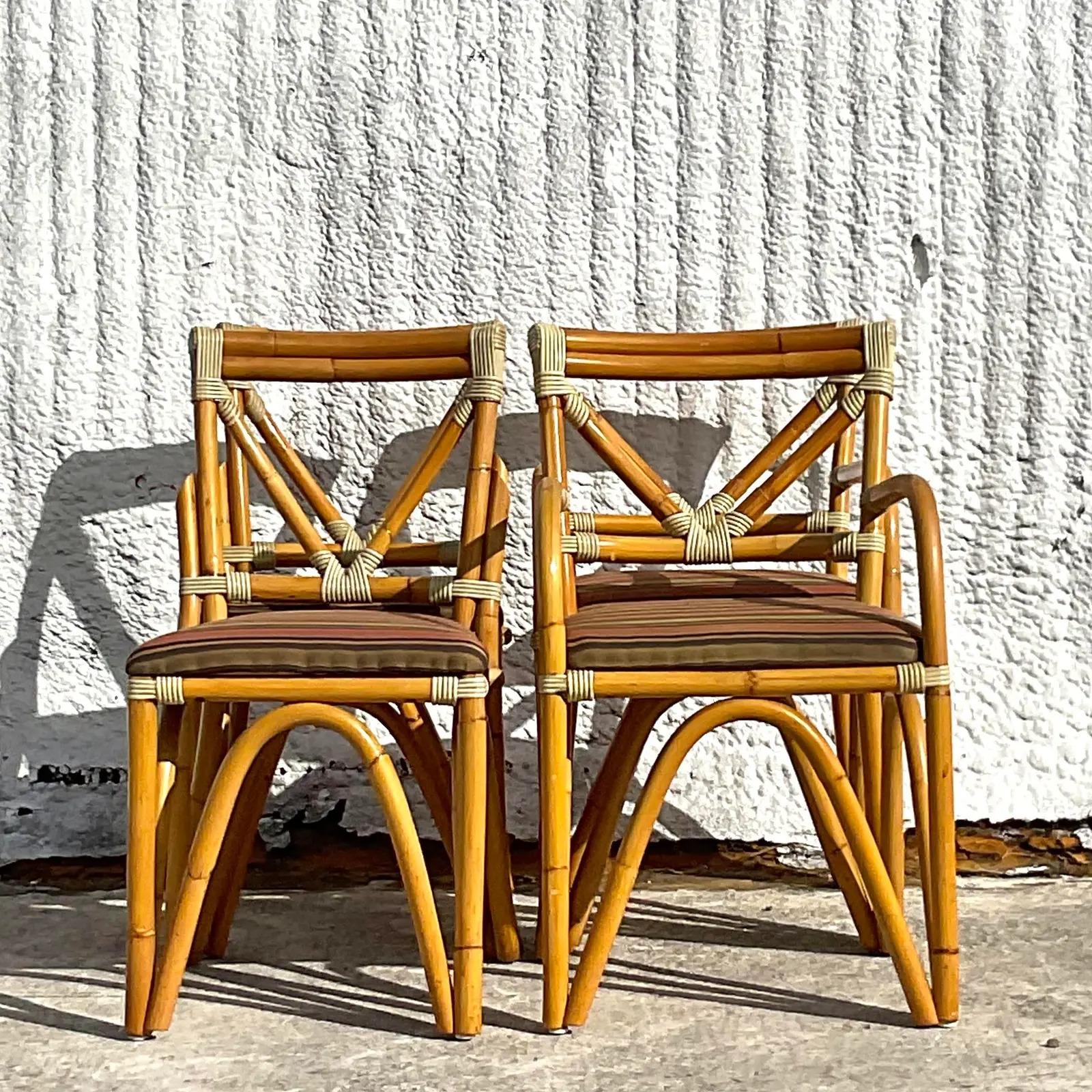 A fabulous set of four vintage Coastal dining chairs. Beautiful bent rattan in a chic and rare design. Beautiful striped wrapped rattan at the joints. Acquired from a Palm Beach estate.