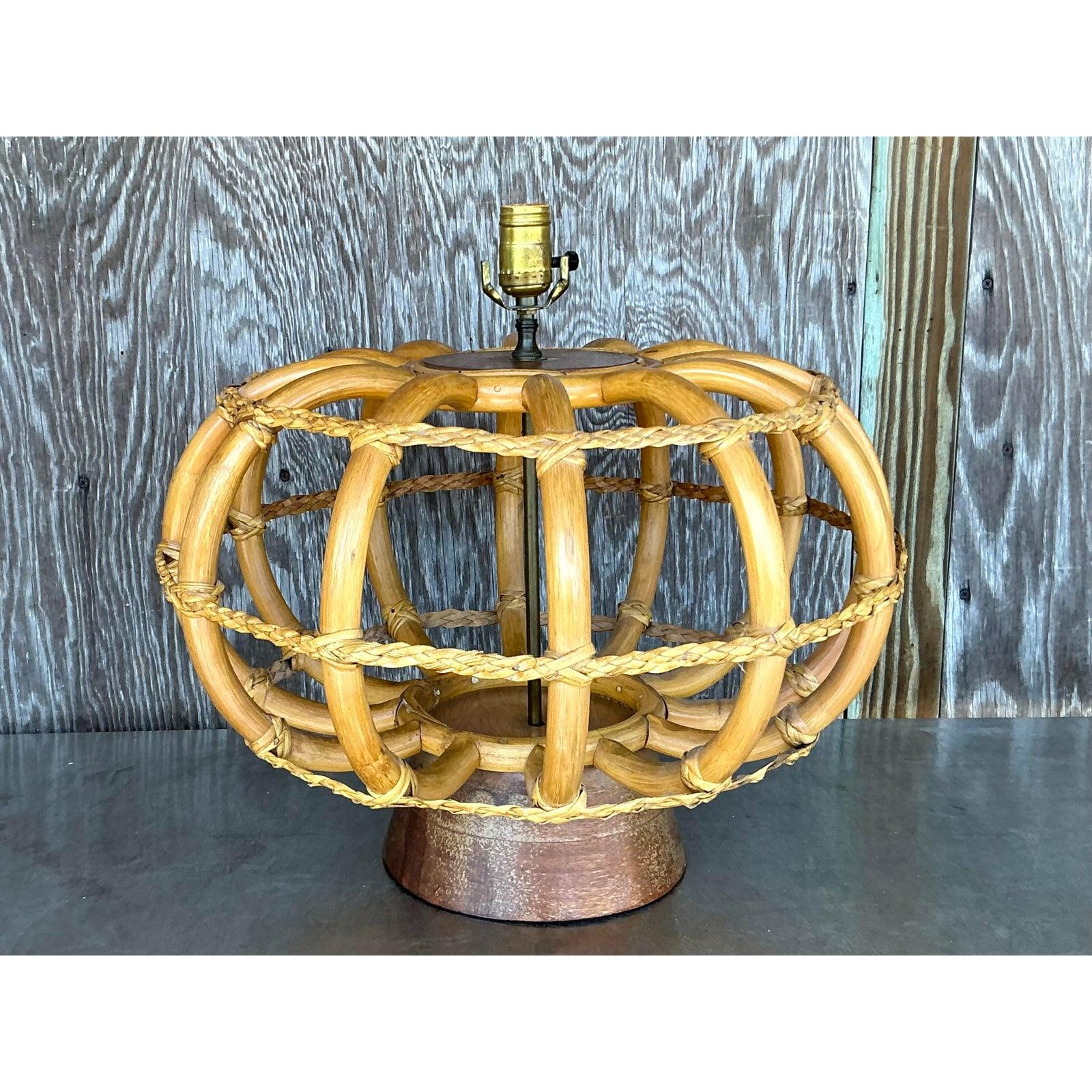 Faites une déclaration frappante avec cette lampe de table monumentale vintage en rotin courbé, une incarnation parfaite du chic côtier et bohème. Sa taille impressionnante et son design sculptural en cage ouverte, fabriqués à partir de rotin