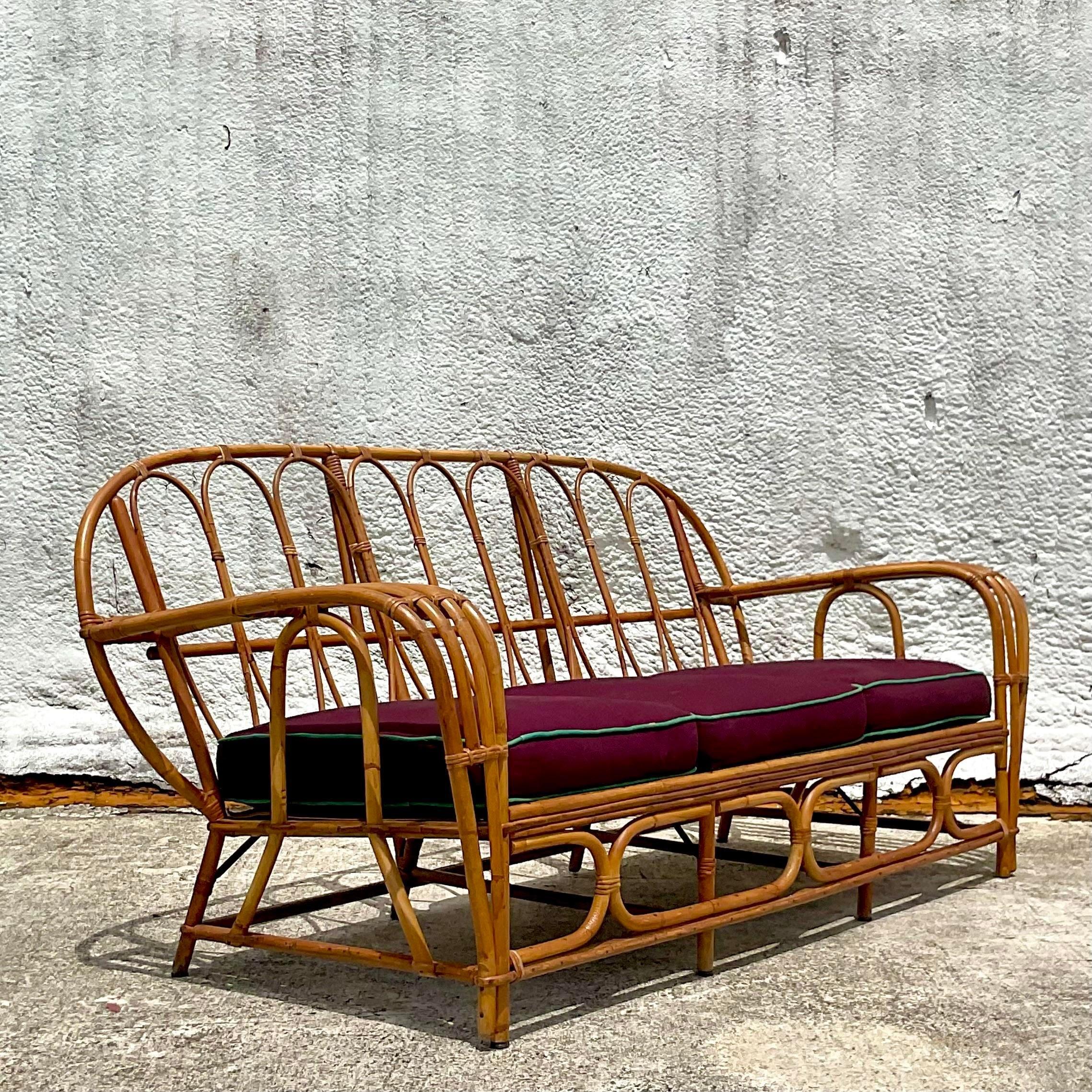 A fabulous vintage Coastal sofa. A chic bent rattan in a cool loop design. Great cushions in a deep aubergine color with a jade tipping.