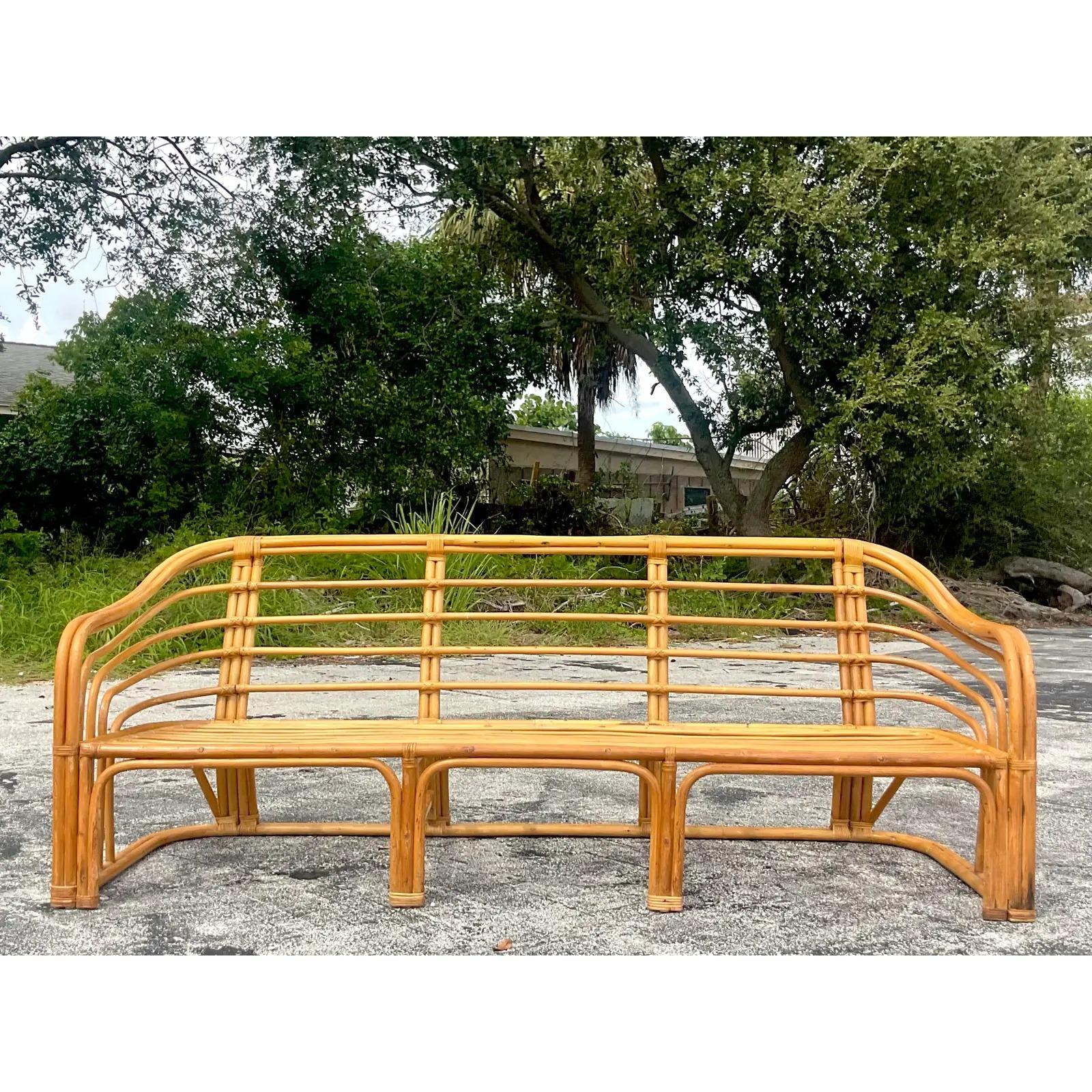 A fabulous vintage Coastal sofa. A beautiful bent rattan in the manner of Brown Jordan. Gorgeous from all sides. Acquired from a Palm Beach estate.