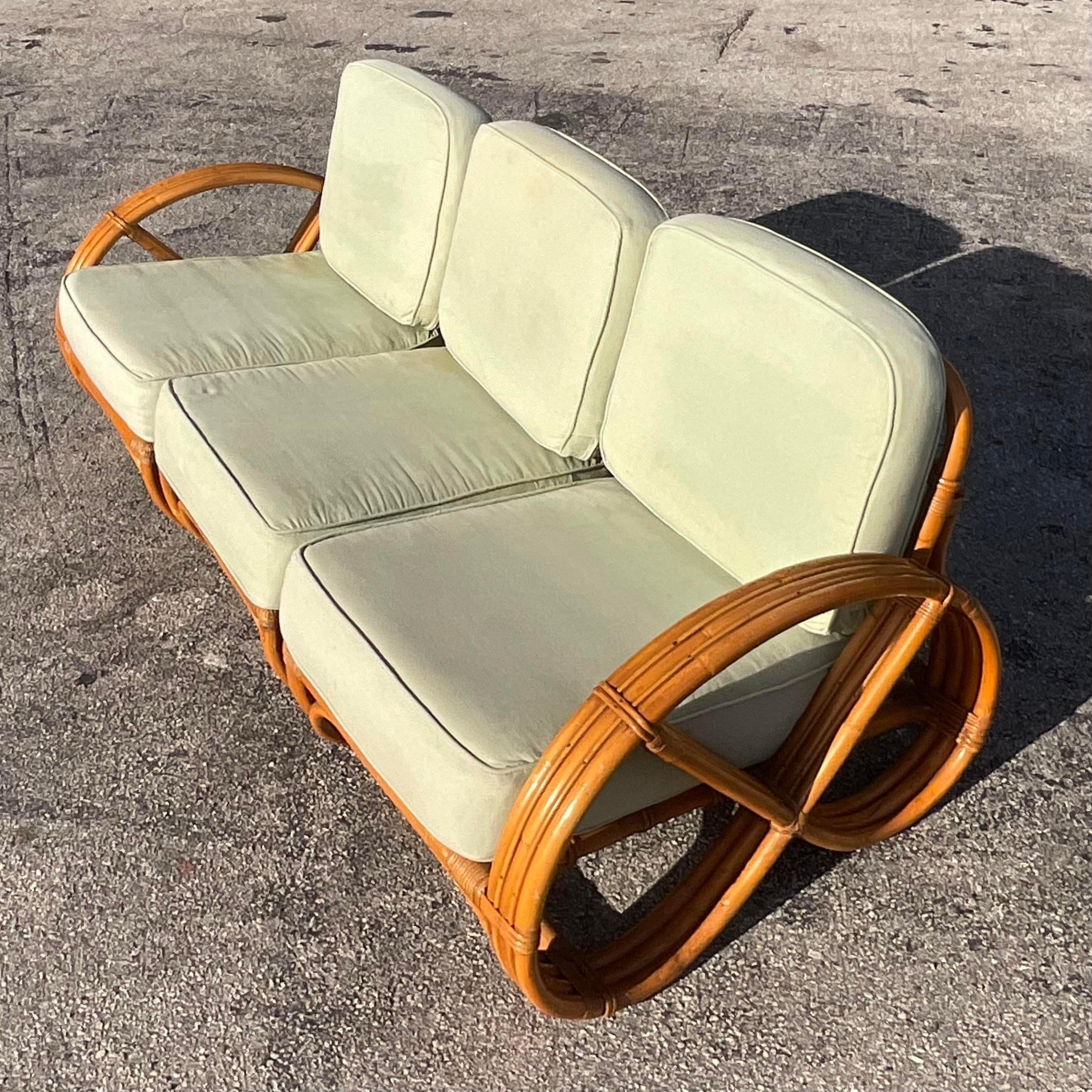 A fantastic vintage Coastal three seat sofa. An iconic shape done in the manner of Paul Frankl. Deep set seats and loop arms. Acquired from a Palm Beach estate