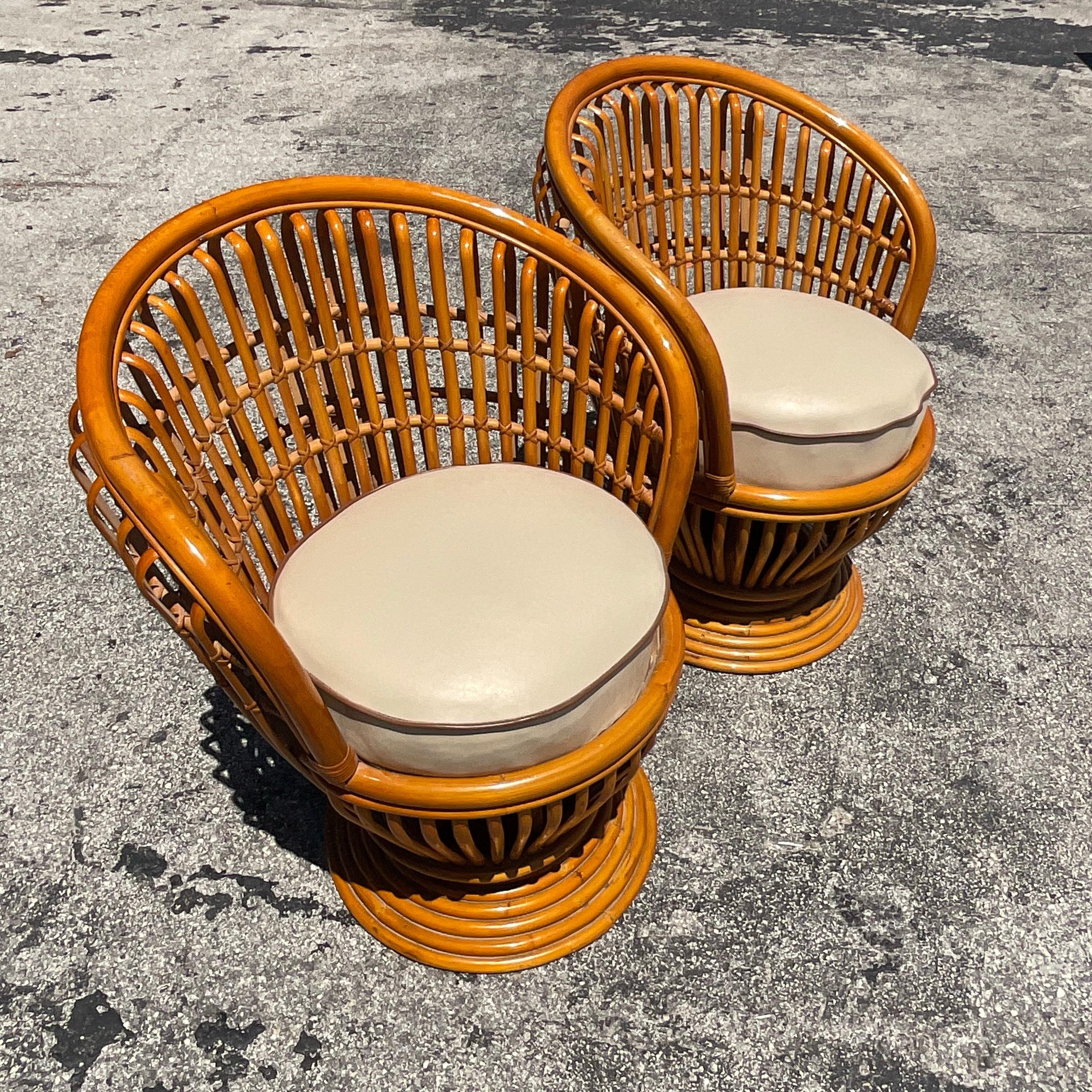 A fantastic pair of vintage Coastal swivel chairs. A chic bent rattan tub shape with a custom leather cushion. Done in the manner of Franco Albini. Acquired from a Palm Beach estate.