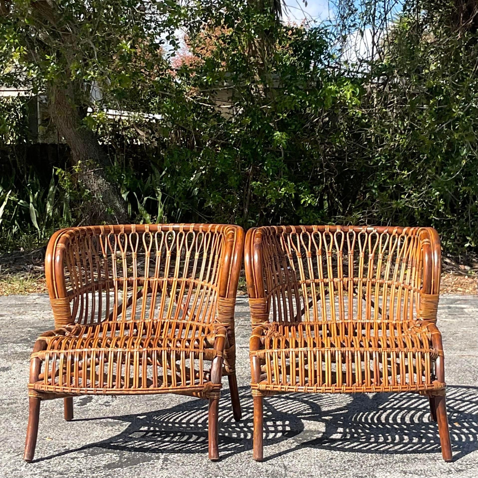 A fabulous pair of vintage Coastal lounge chairs. Gorgeous bent rattan in a chic wave design. Acquired from a Palm Beach estate.