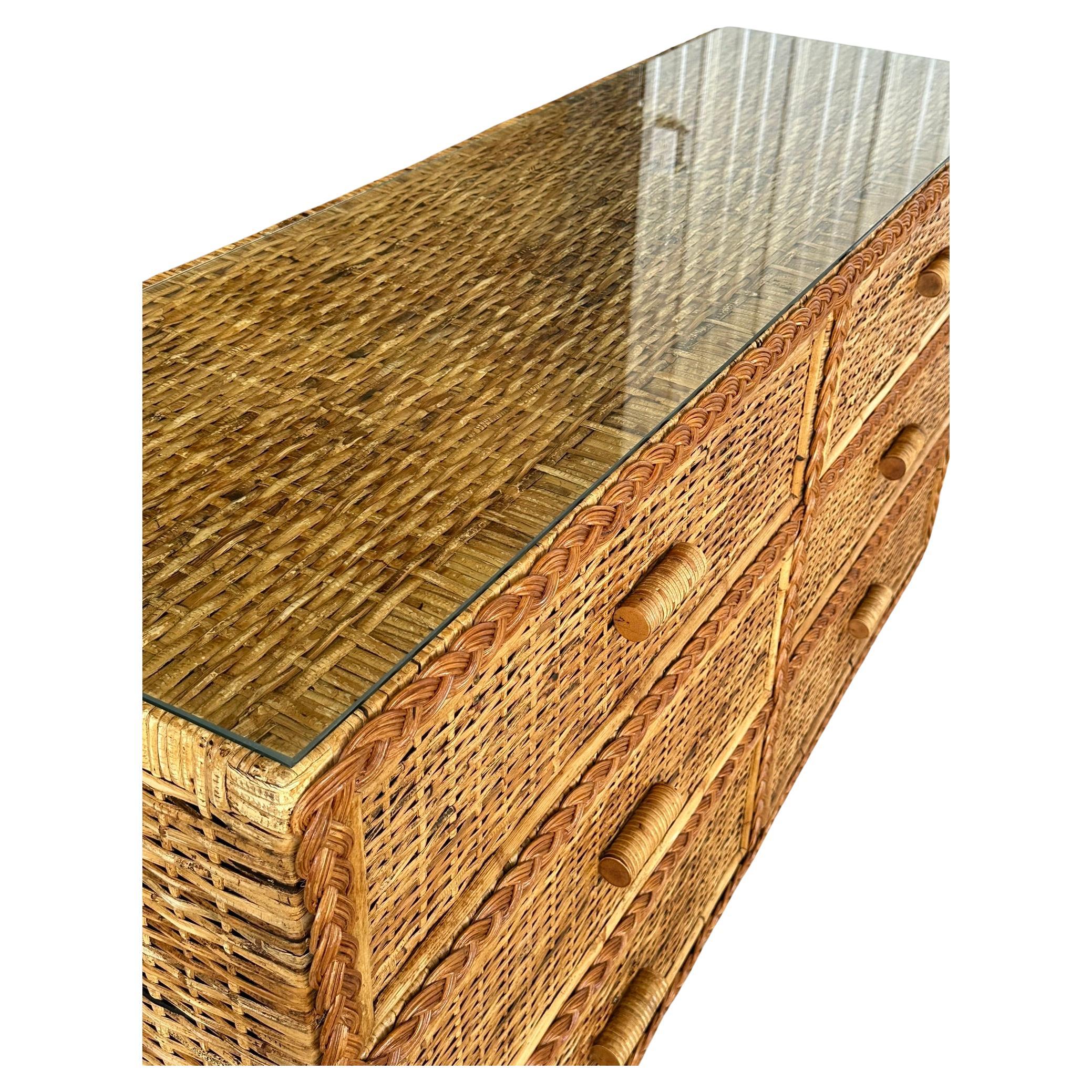 
Introducing a beautifully refinished vintage six-drawer dresser, featuring an intricate rattan weave design. This exceptional piece showcases a rattan braid front, rattan trim, and rattan handle pulls, making it a perfect addition for those seeking