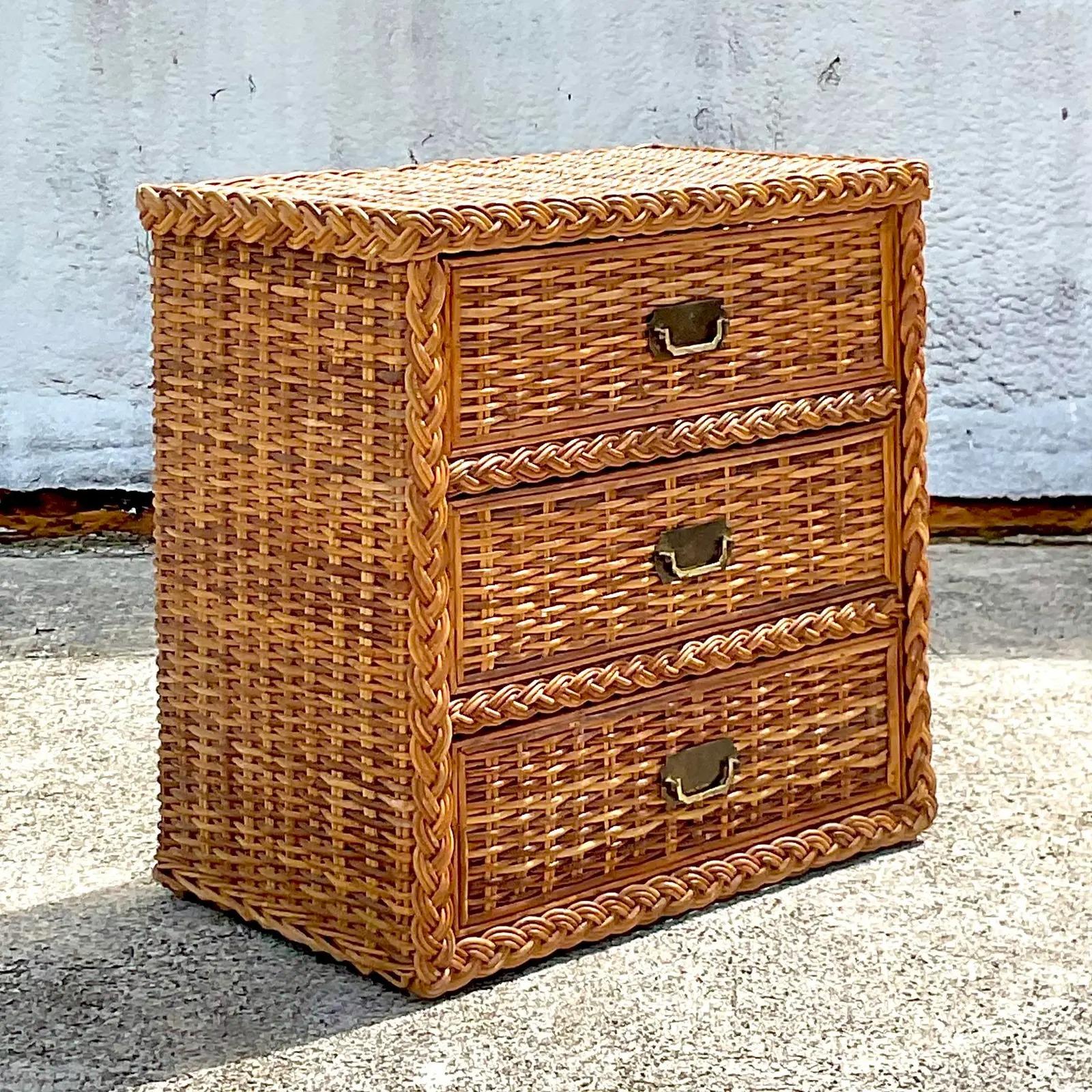 A fabulous vintage Coastal chest of drawers. Beautiful thicker rattan in a beautiful honey brown color. Chic braided trim along the edge. Brass campaign hardware. Acquired from a Palm Beach estate.