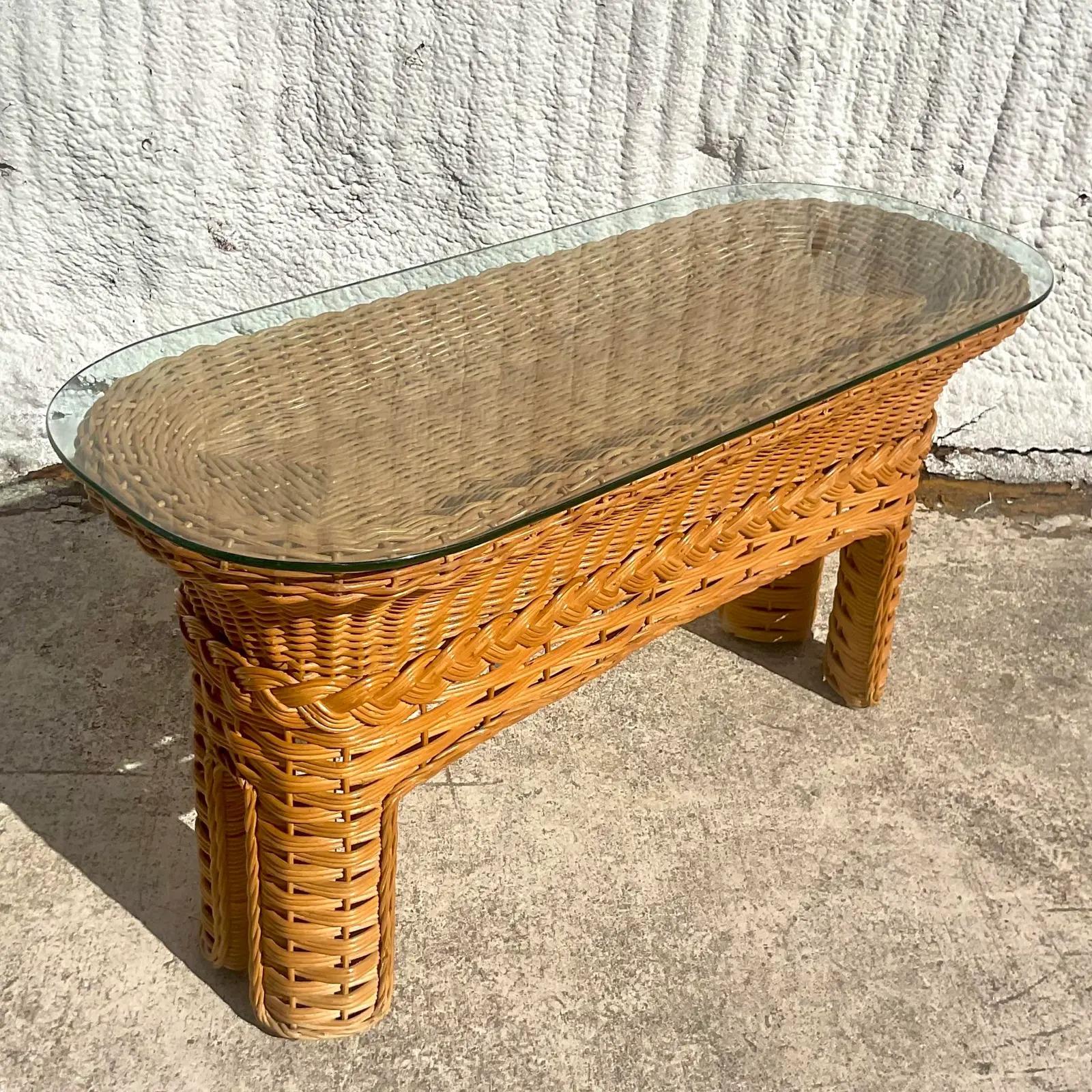 A fantastic vintage Coastal console table. Beautiful woven rattan with a chic braided band detail. Glass top that rests over a shallow valley. Perfect for your shell collection. Acquired from a Palm Beach estate.