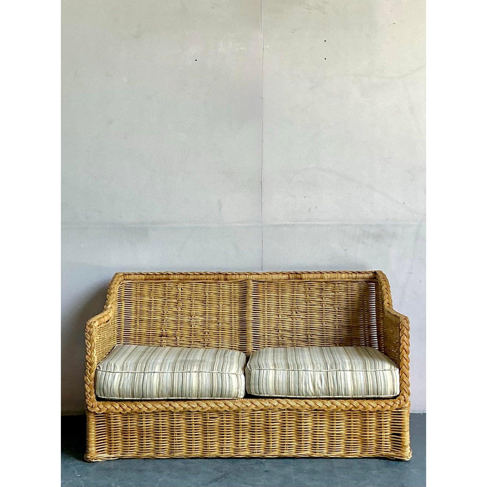 Discover the captivating allure of this Vintage Coastal Braided Rattan Loveseat, an exquisite piece embodying the relaxed yet sophisticated design ethos of the 1970s. Handcrafted with meticulous braided rattan, this loveseat showcases a beautiful