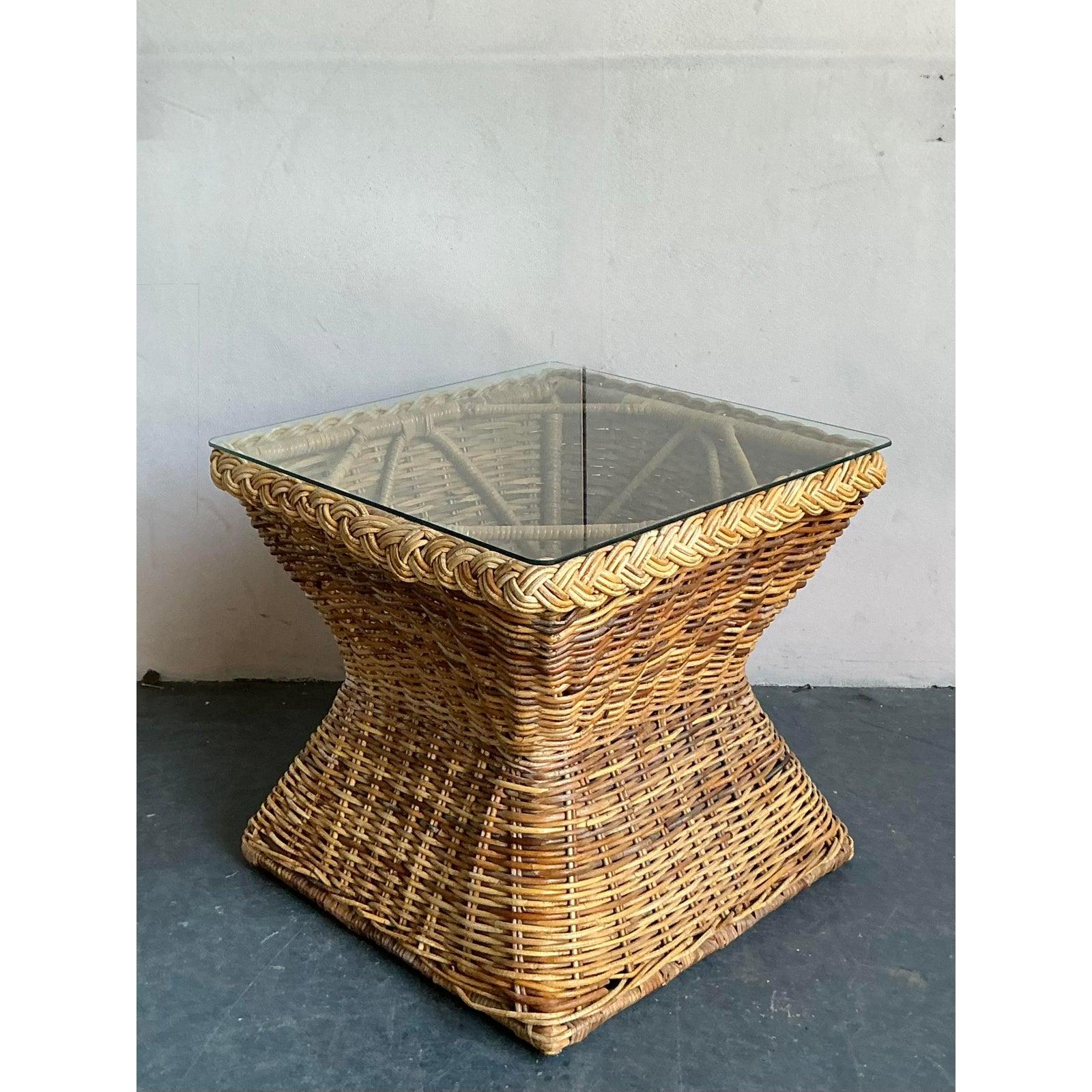 Dieser bezaubernde Beistelltisch im Vintage-Stil mit geflochtenem Rattansockel und Klarglasplatte steht für die entspannte Eleganz des Lebens an der Küste. Dieses Stück strahlt eine zeitlose, luftige Ästhetik aus und eignet sich perfekt, um jedem