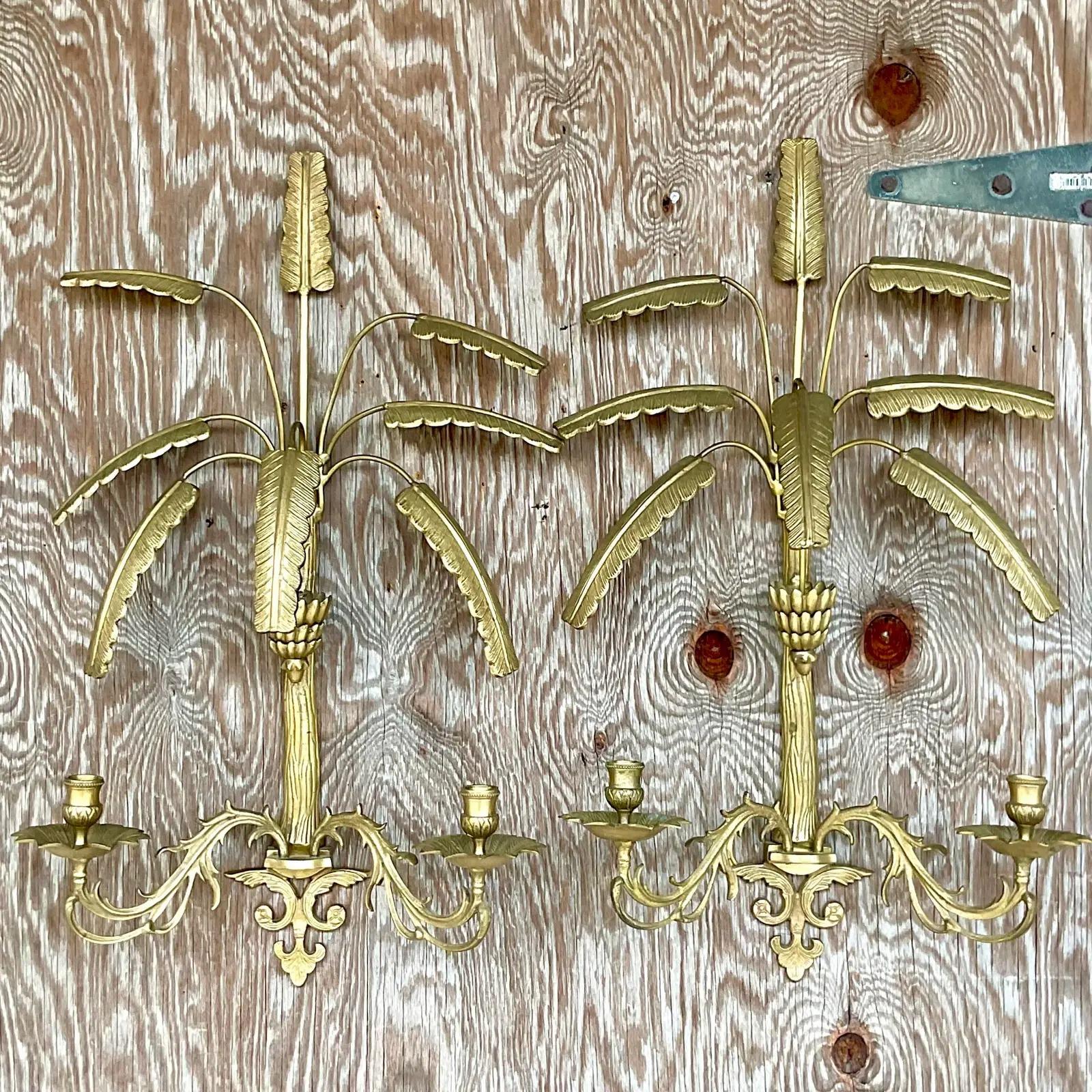 Fantastic pair of vintage Regency brass wall candelabras. Beautiful palm tree design with two candle holders each. Acquired from a Palm Beach estate.