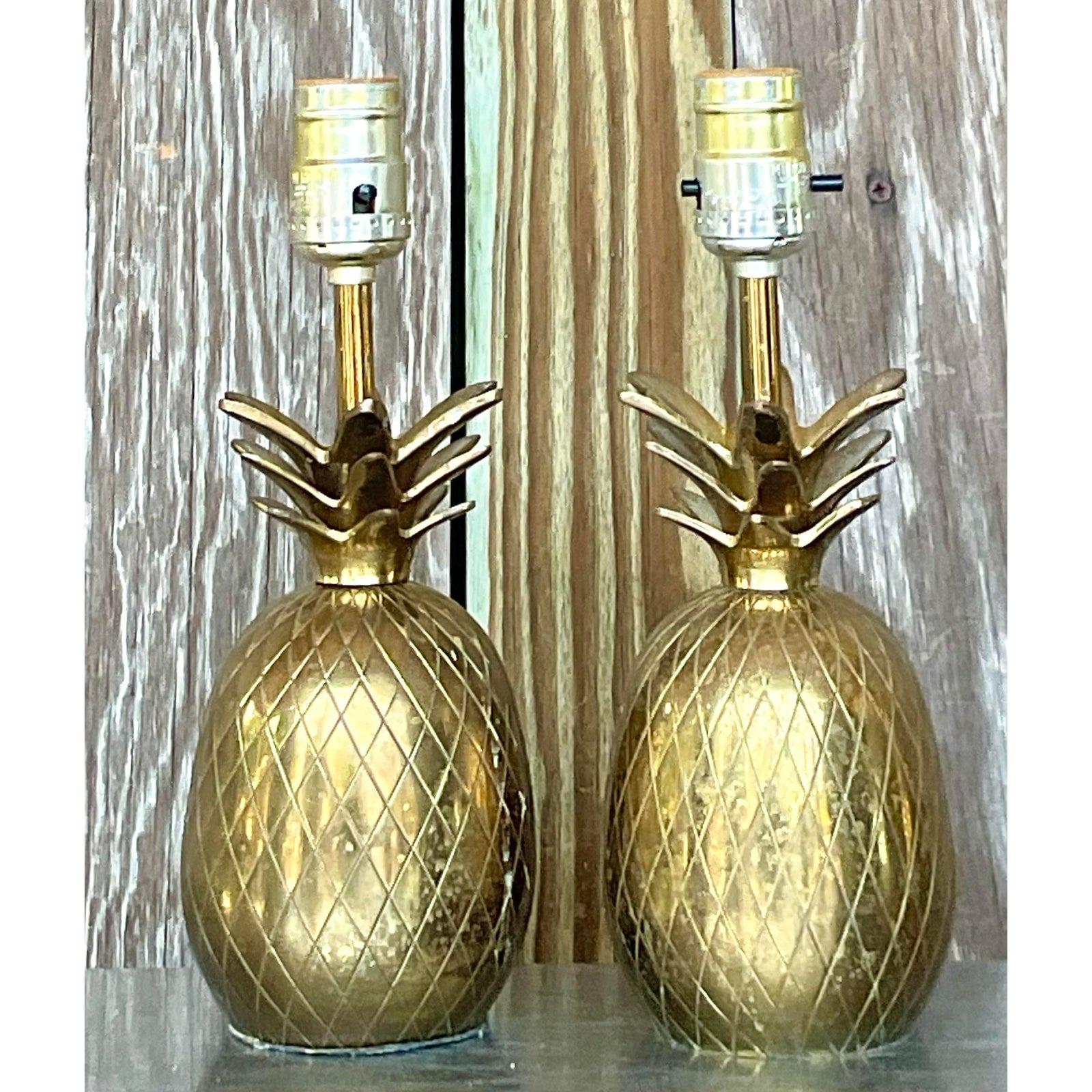 Brighten your space with a touch of coastal charm using this pair of Vintage petite Coastal Brass Pineapple Lamps. These American-style lamps boast intricate brass detailing in the shape of pineapples, symbolizing hospitality and warmth. Perfect for