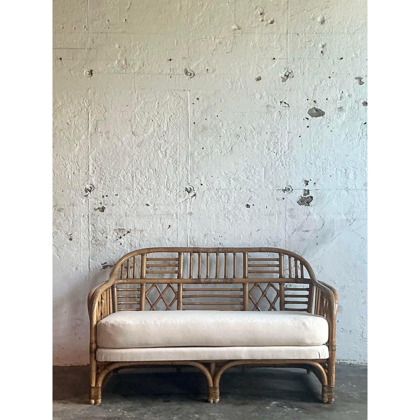 Capta el encanto atemporal de la realeza costera con este exquisito sillón de ratán vintage, diseñado en el codiciado estilo Brighton Pavilion. Hecha a mano por expertos con bambú curvado y ratán, presenta una elegante estructura calada y líneas