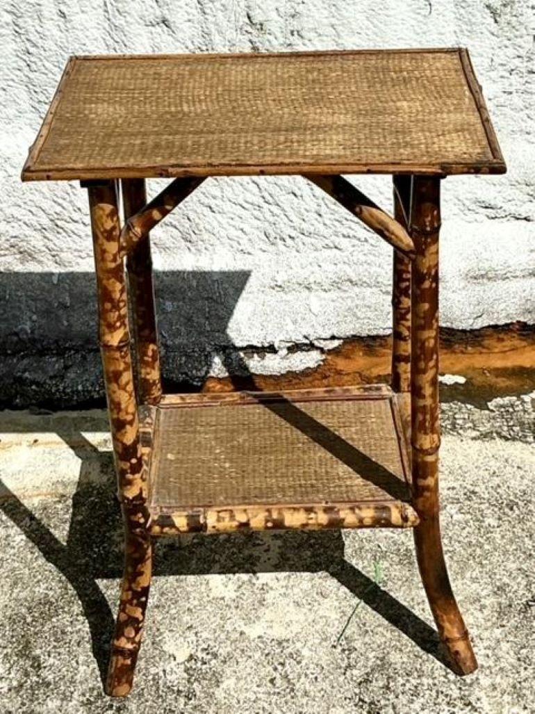 Peppen Sie Ihre Küstendekoration mit diesem atemberaubenden Beistelltisch aus gebranntem Bambus im Vintage-Stil auf. Mit seiner natürlichen, verwitterten Patina fängt sein kompliziertes Flechtmuster die Essenz des entspannten Charmes der Küste ein.
