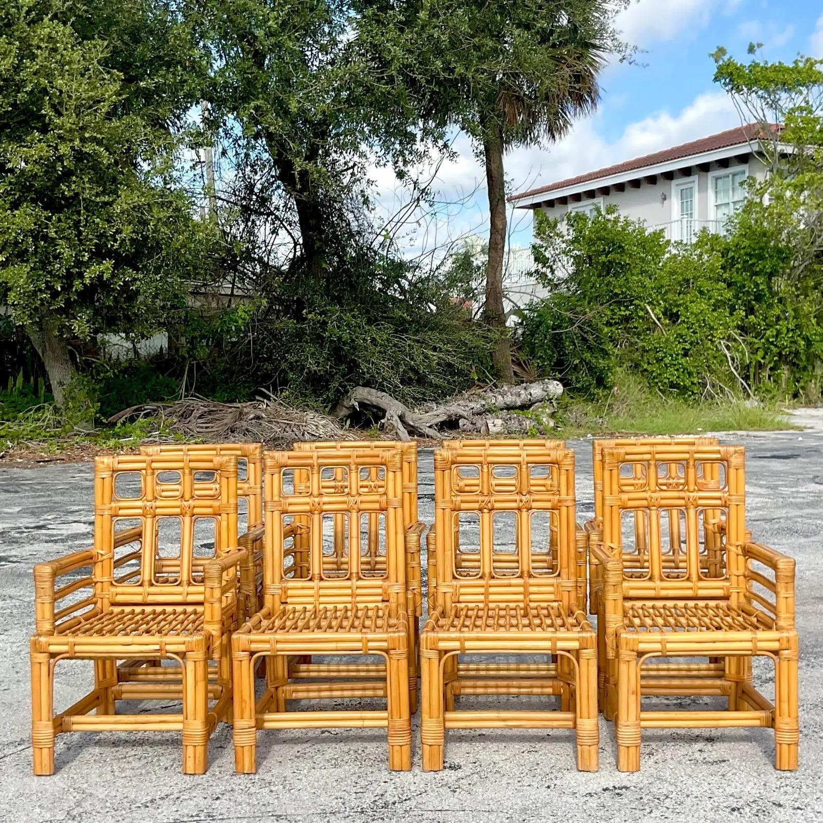 A fantastic set of eight Coastal rattan dining chairs. Made by the iconic Calif-Asia group. Beautiful bent rattan in a chic streamline design. Six arm chairs and two side chairs. Tagged on the bottom. Acquired from a Palm Beach estate.