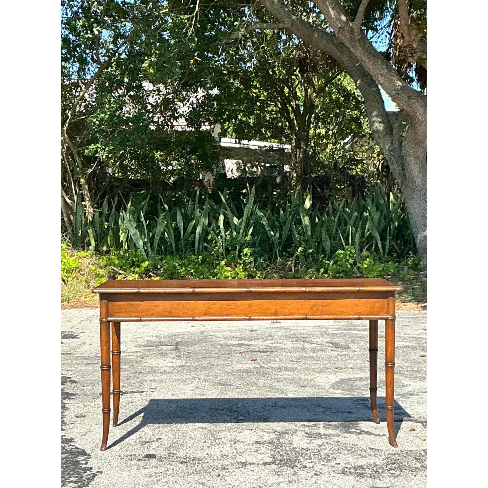 Infuse your space with a relaxed yet refined charm using this Vintage Coastal Console Table, featuring beautifully carved faux bamboo legs and edges. The low-profile silhouette and warm mahogany finish offer a versatile design perfect for entryways,