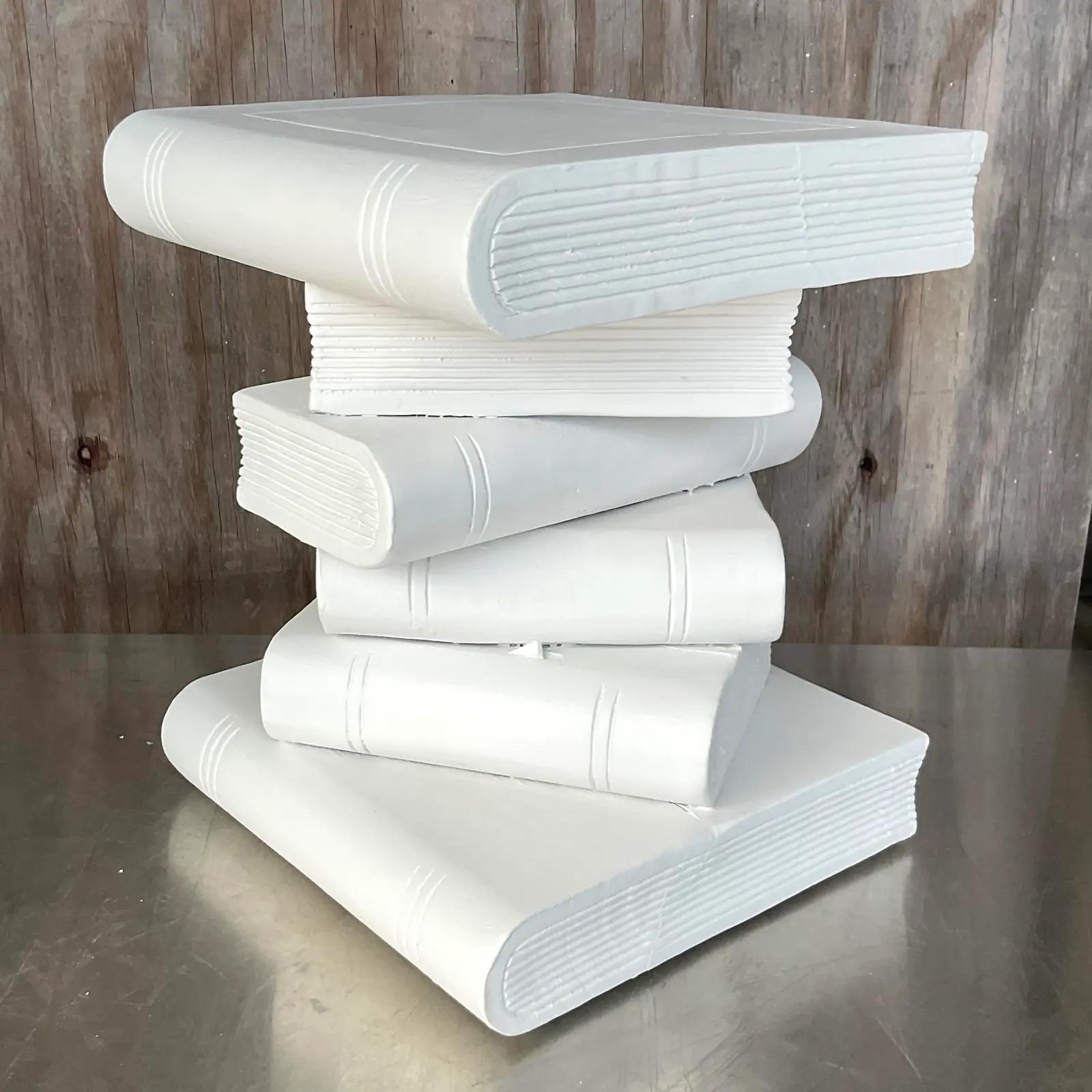 A brilliant Boho carved wooden side table. A charming stack of books painted a bright white. A Palm Beach classic. Acquired from a Palm Beach estate.