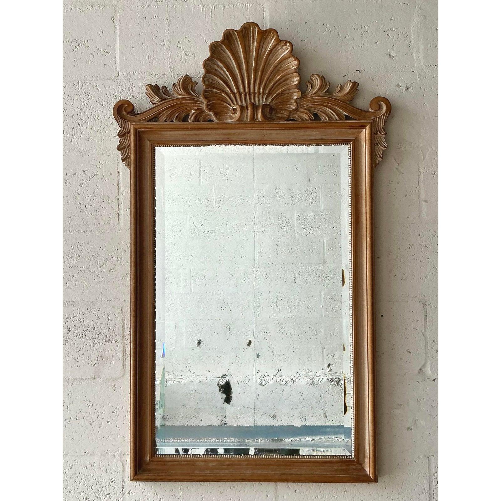 Aggiungi un tocco di grazia costiera senza tempo ai tuoi interni con questo squisito specchio vintage in legno intagliato. Il design è magistralmente coronato da un ornato frontone a conchiglia intagliato a mano, un classico simbolo dell'eleganza