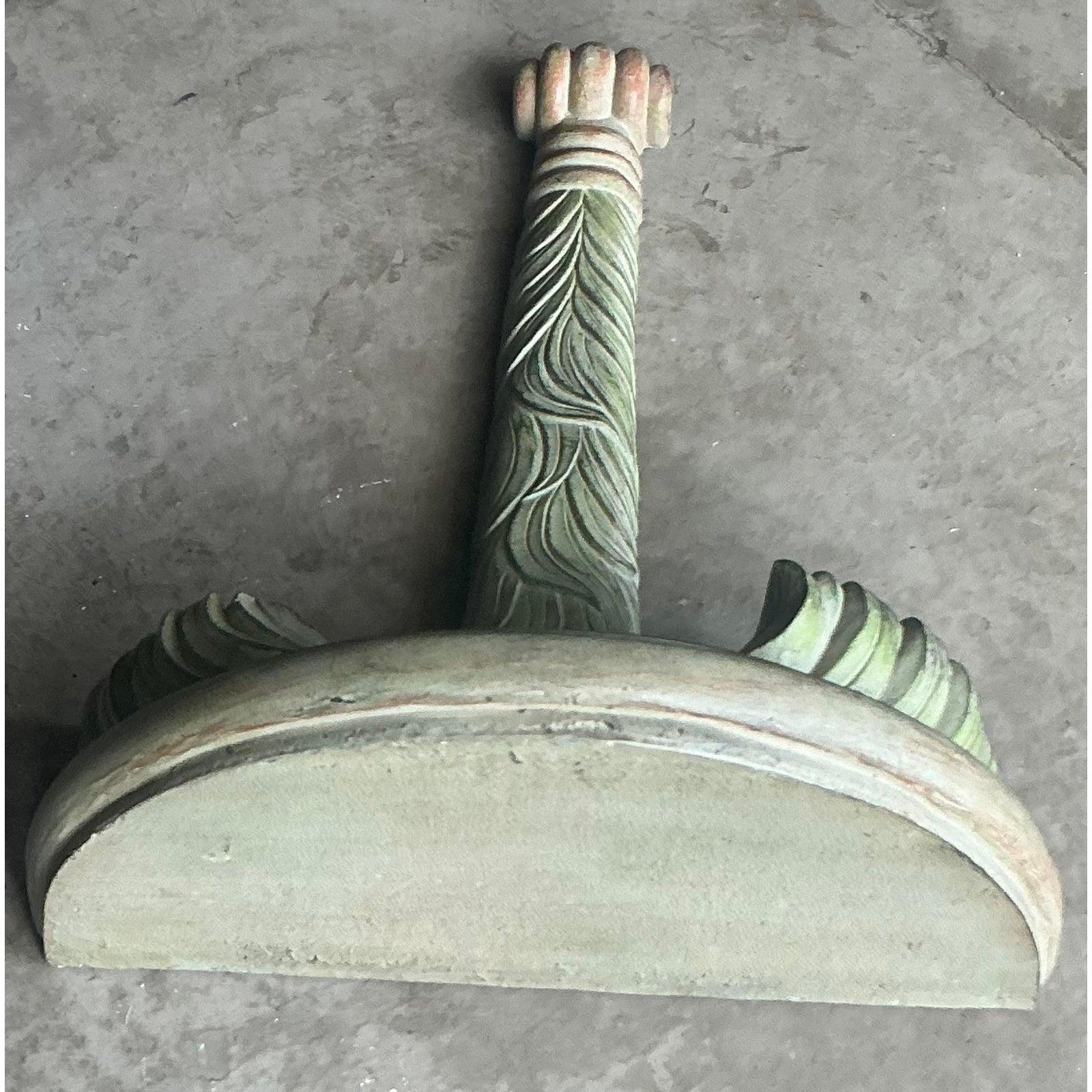 Fangen Sie die schicke, tropische Essenz des Palm Beach Regency mit dieser exquisiten Vintage-Wandhalterung ein. Dieses meisterhaft handgeschnitzte skulpturale Stück zeigt eine Gruppe stilisierter Palmwedel, die ein klassisches Demi-Lune-Regal