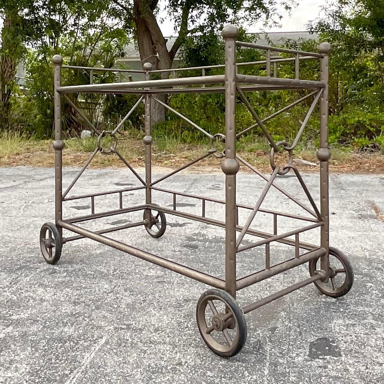 A fabulous vintage Coastal bar cart. A chic target back design in a cast aluminum. Great for places close to the ocean. Inset glass shelves and caster wheels for easy movement. Acquired from a Palm Beach estate.