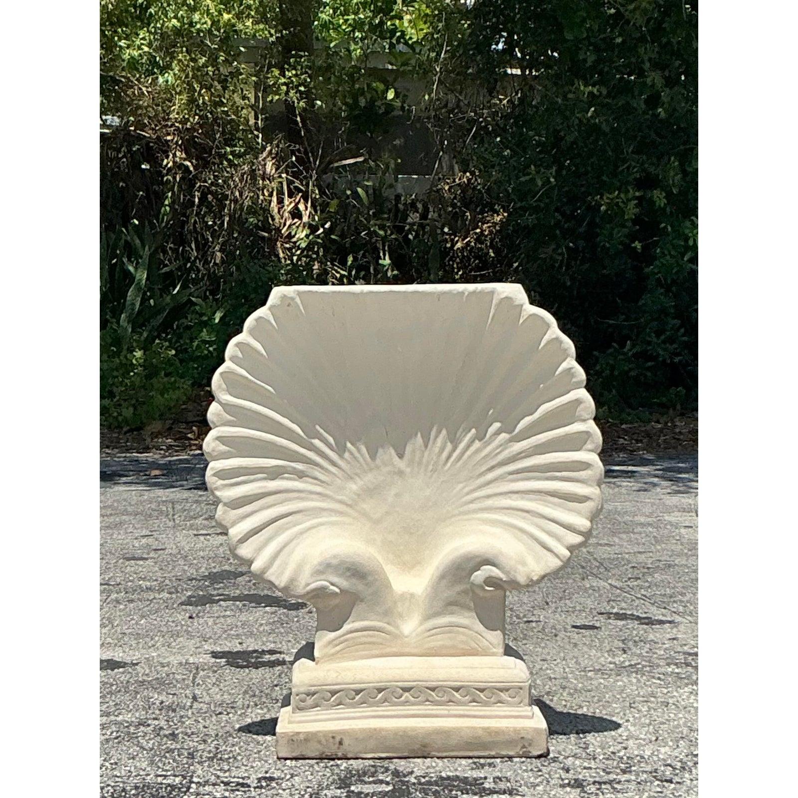 Bring the serene elegance of the seashore into your home or garden with this exquisite vintage coastal cast concrete clam shell pedestal. This magnificent piece is masterfully sculpted in the graceful form of an open clam shell, boasting beautifully