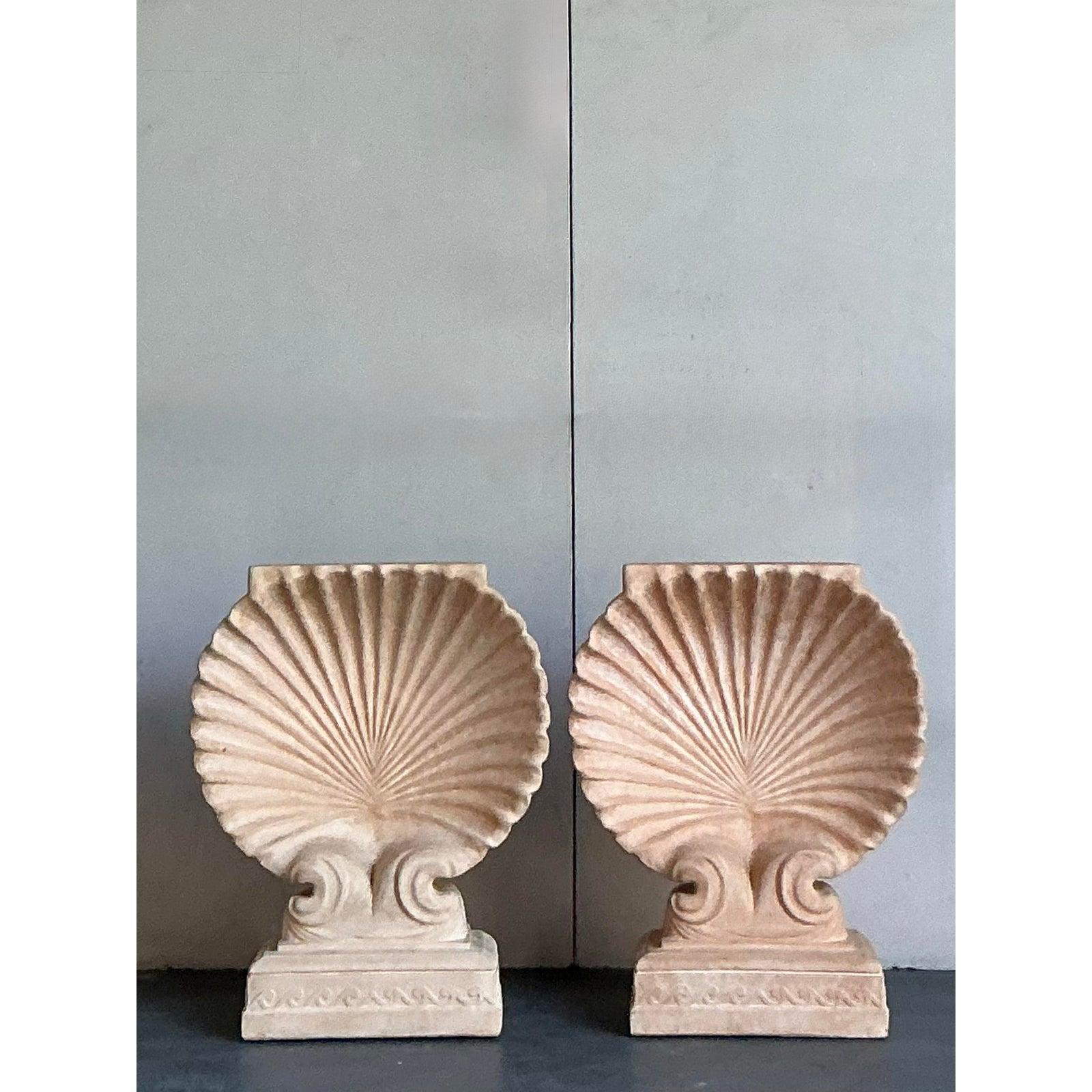 Infondi nel tuo spazio un'eleganza architettonica e un tocco di grandezza costiera con questa eccezionale coppia di piedistalli vintage in cemento fuso. Ogni pezzo presenta un motivo a conchiglia magistralmente scolpito, la cui scanalatura