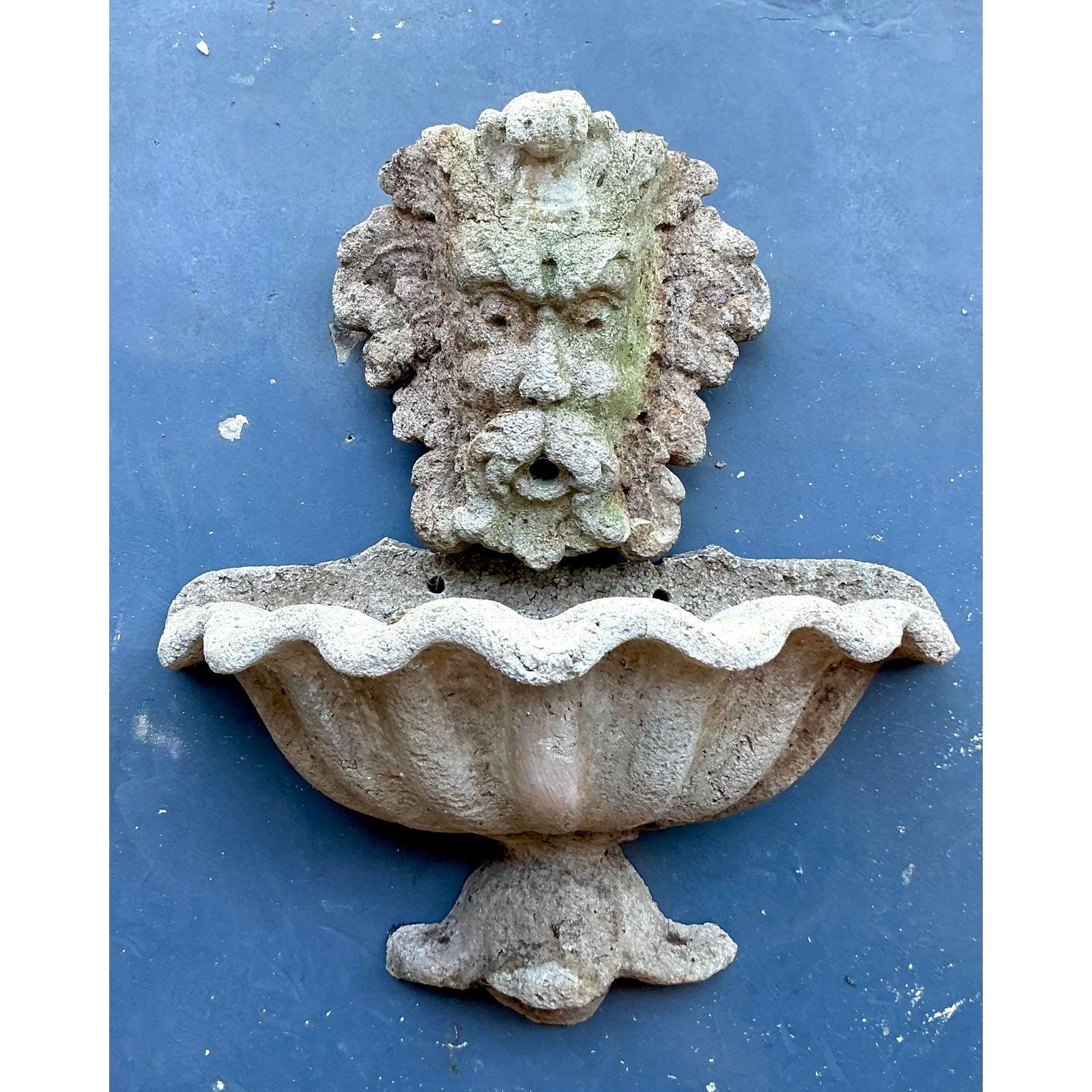 Invite an enchanting whisper of old-world charm into your garden or interior with this captivating Vintage Coastal Cast Stone Grotesque Face & Clamshell Wall Fountain. This unique piece of sculptural artistry features a wonderfully detailed,